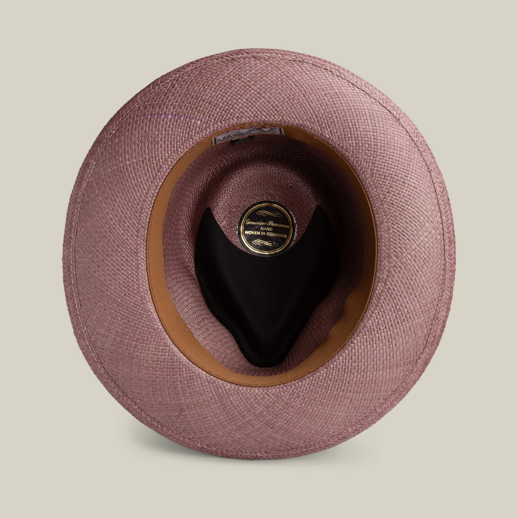 Top view of the John Sr. teardrop fedora by Goorin Bros.—pink toquilla straw, black interior lining, brown inner band—displayed on a light beige background. Stylish and provides UPF 50 sun protection.