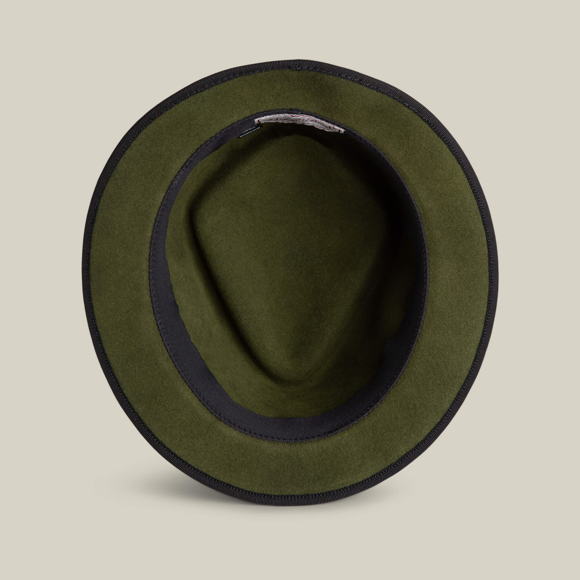 Top view of the Goorin Bros. Slick Carter olive green wool short brim felt hat with a black inner band, styled on a plain beige background.