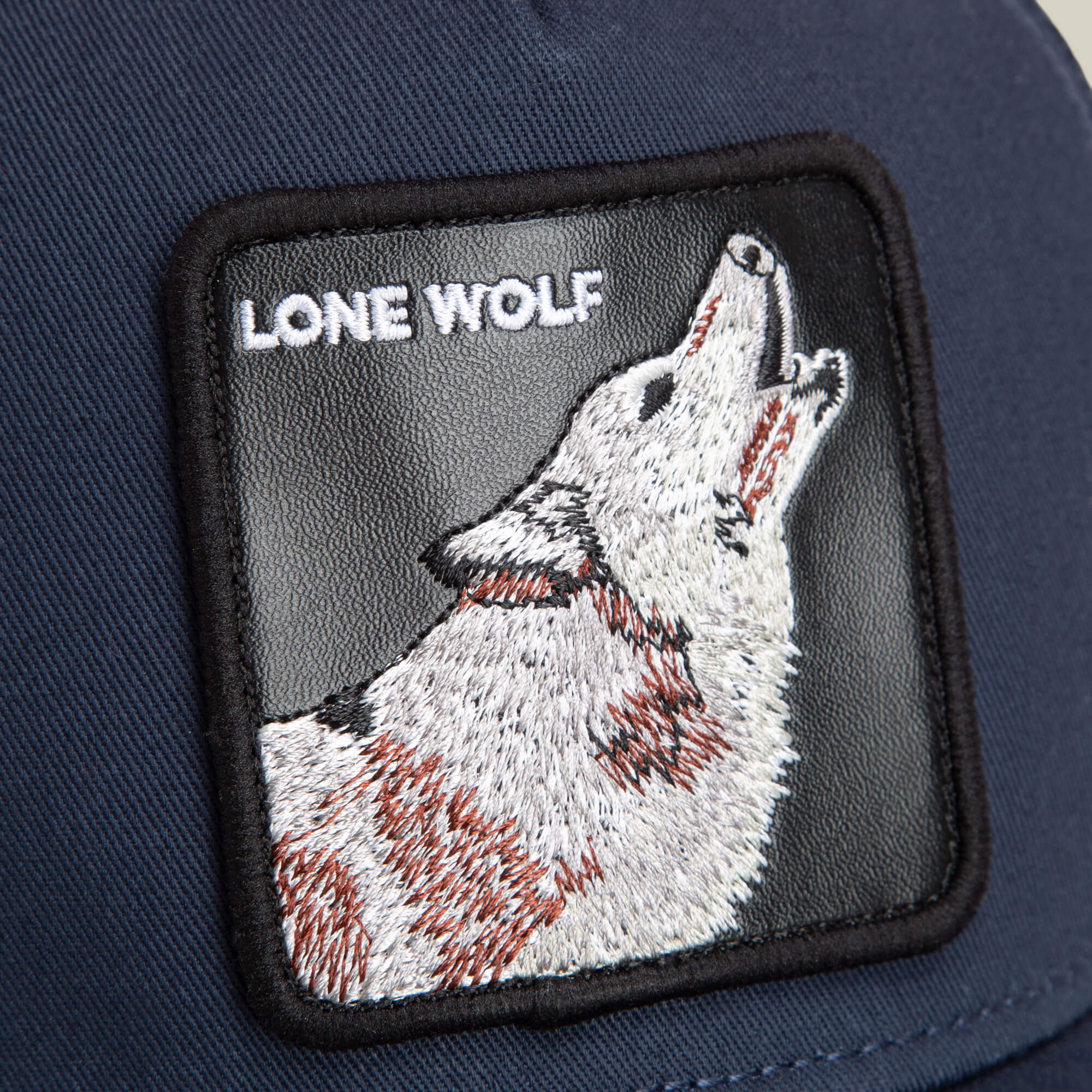 The Farm’s “The Lone Wolf” is a navy blue cap with a stitched patch showing a howling wolf and the words LONE WOLF in white—ideal for those with an independent spirit.