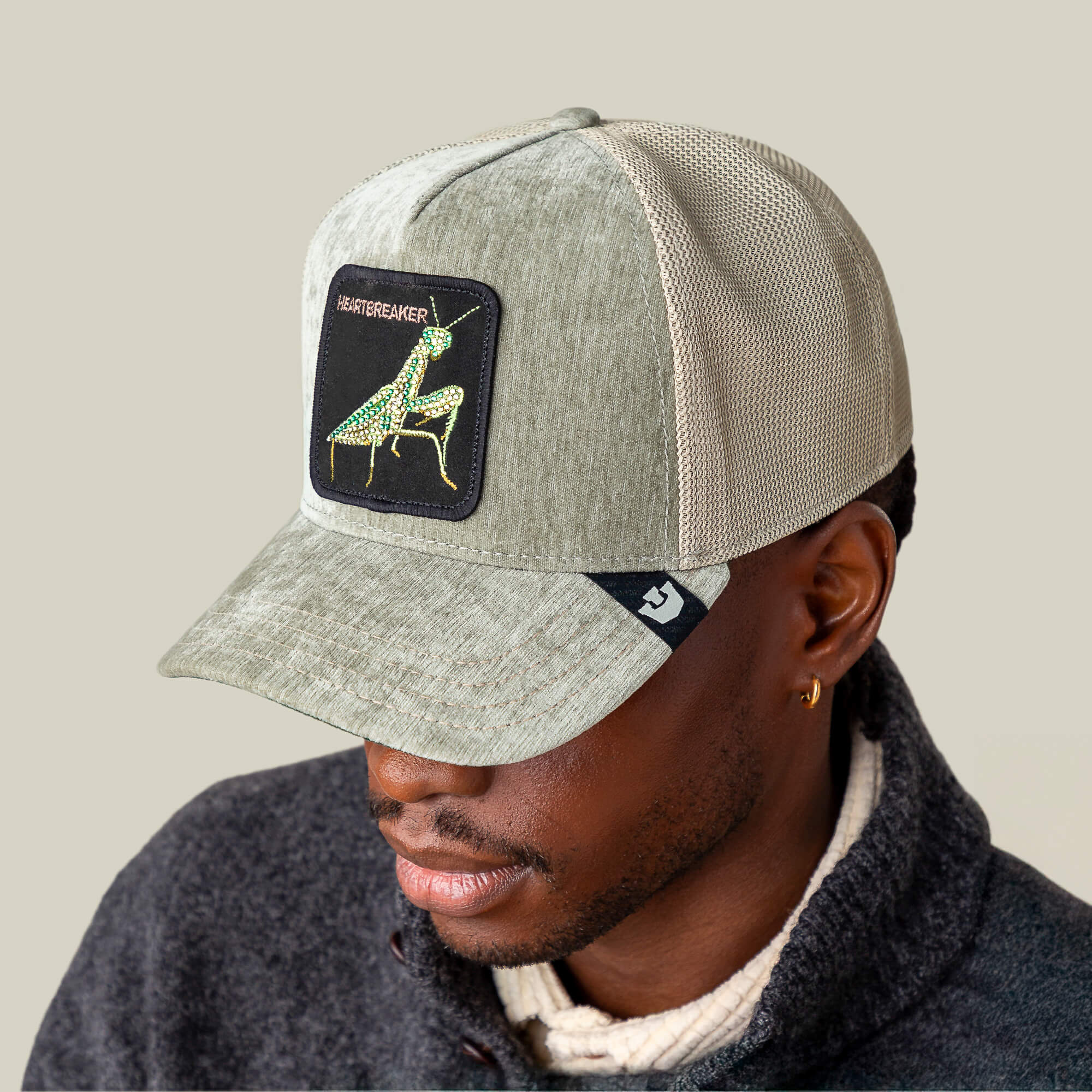 A person wearing the Goorin Bros. Iced Mantis mesh baseball cap in light gray champagne, featuring a patch with a Praying Mantis.