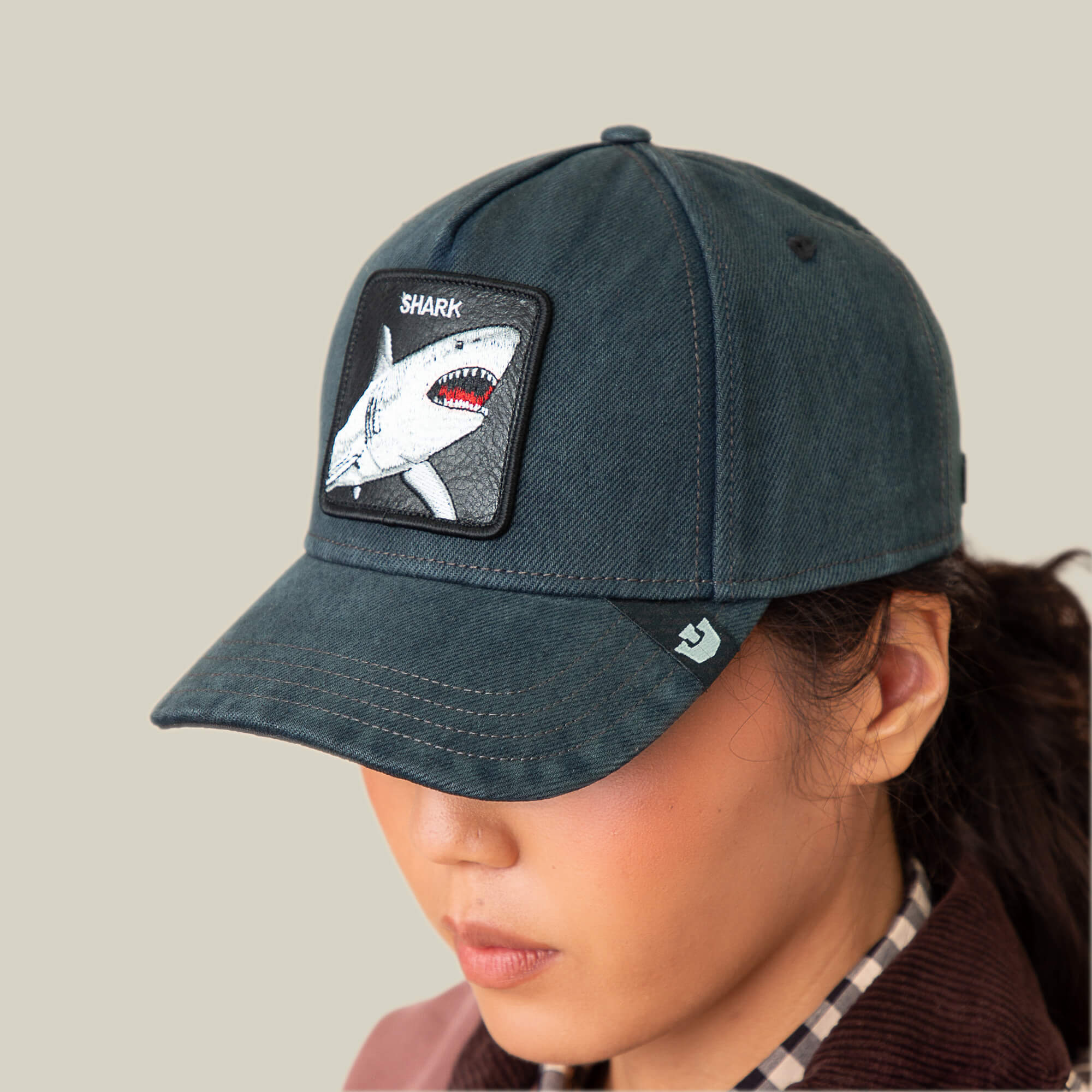 Someone wearing the Goorin Bros. "Smurf" dark blue surf-punk cap with a jagged grin patch on the front, head slightly tilted down, set against a plain background.