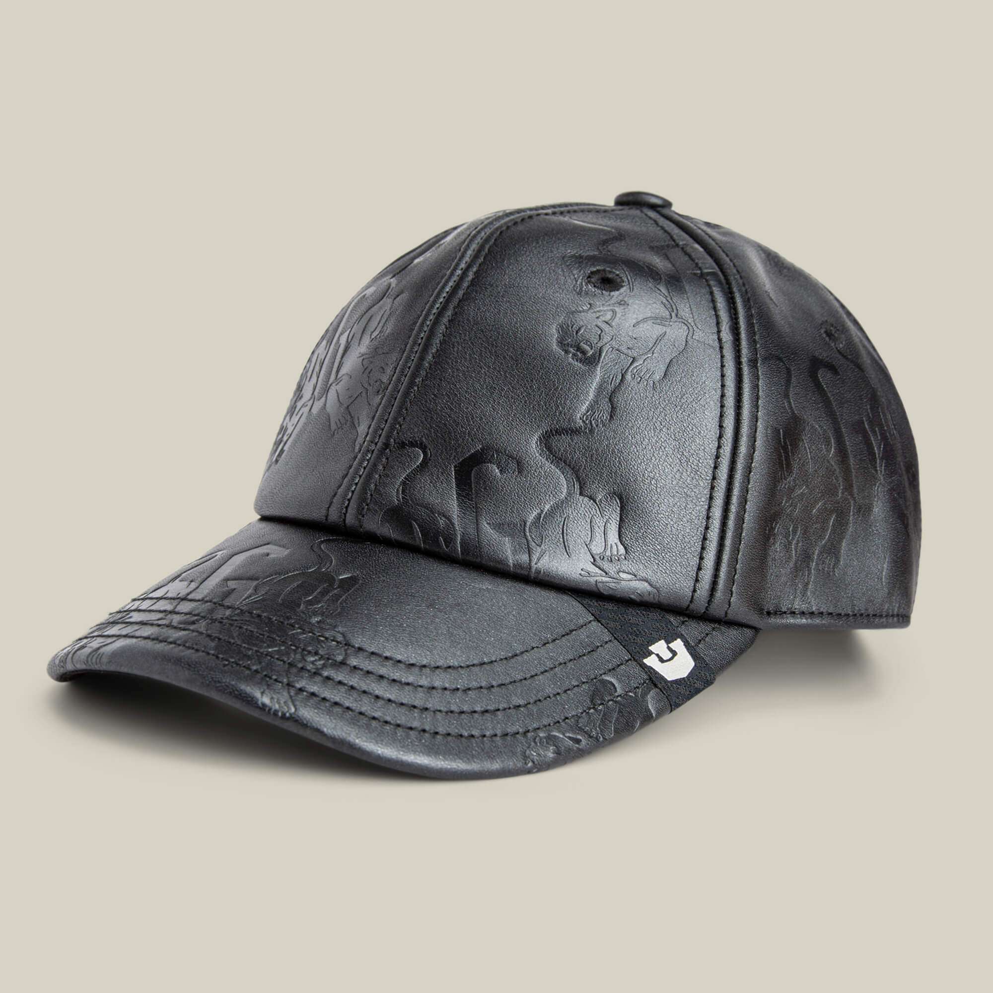 The Goorin Bros. "Put a Panther On It" is a black leather baseball cap featuring embossed animal figures and a small white logo on the brim, shown against a plain beige background.
