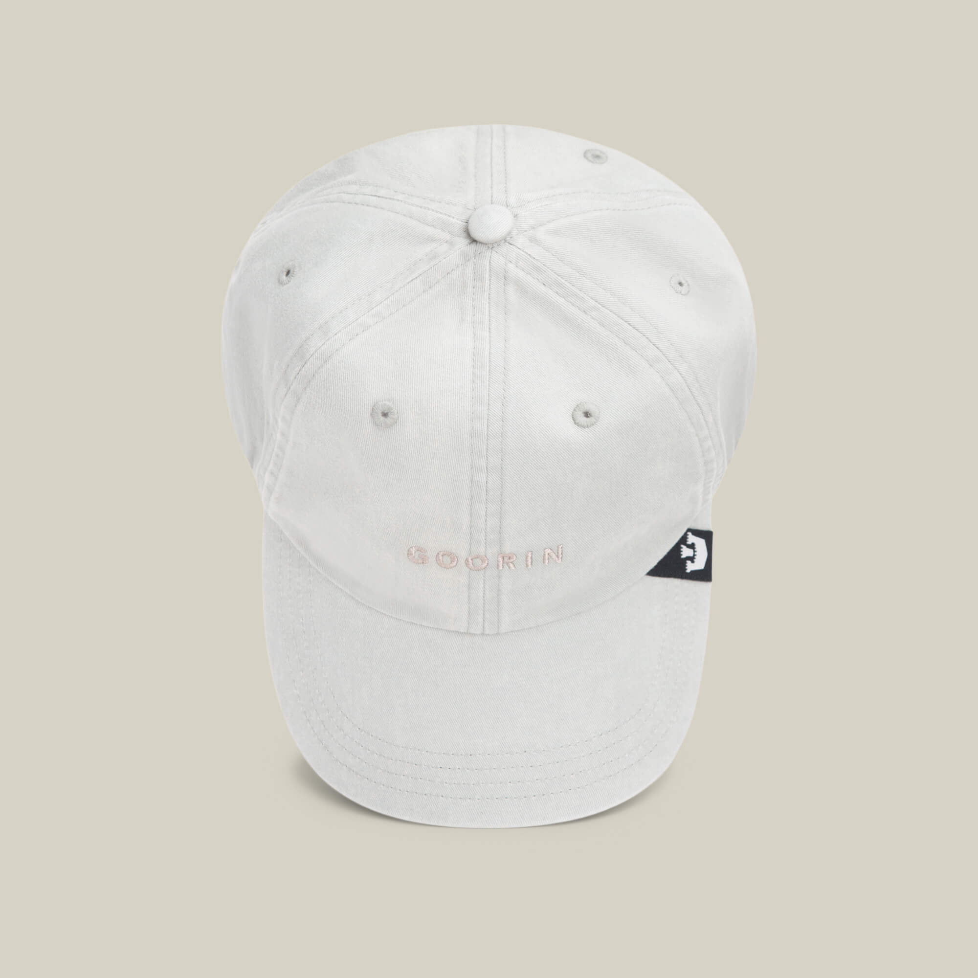 The Papa Cap Italiano by Goorin Bros. features classic white fabric, visible stitching, a small embroidered GOORIN logo on the front, and a black side tag with a white graphic—timeless style in every detail.