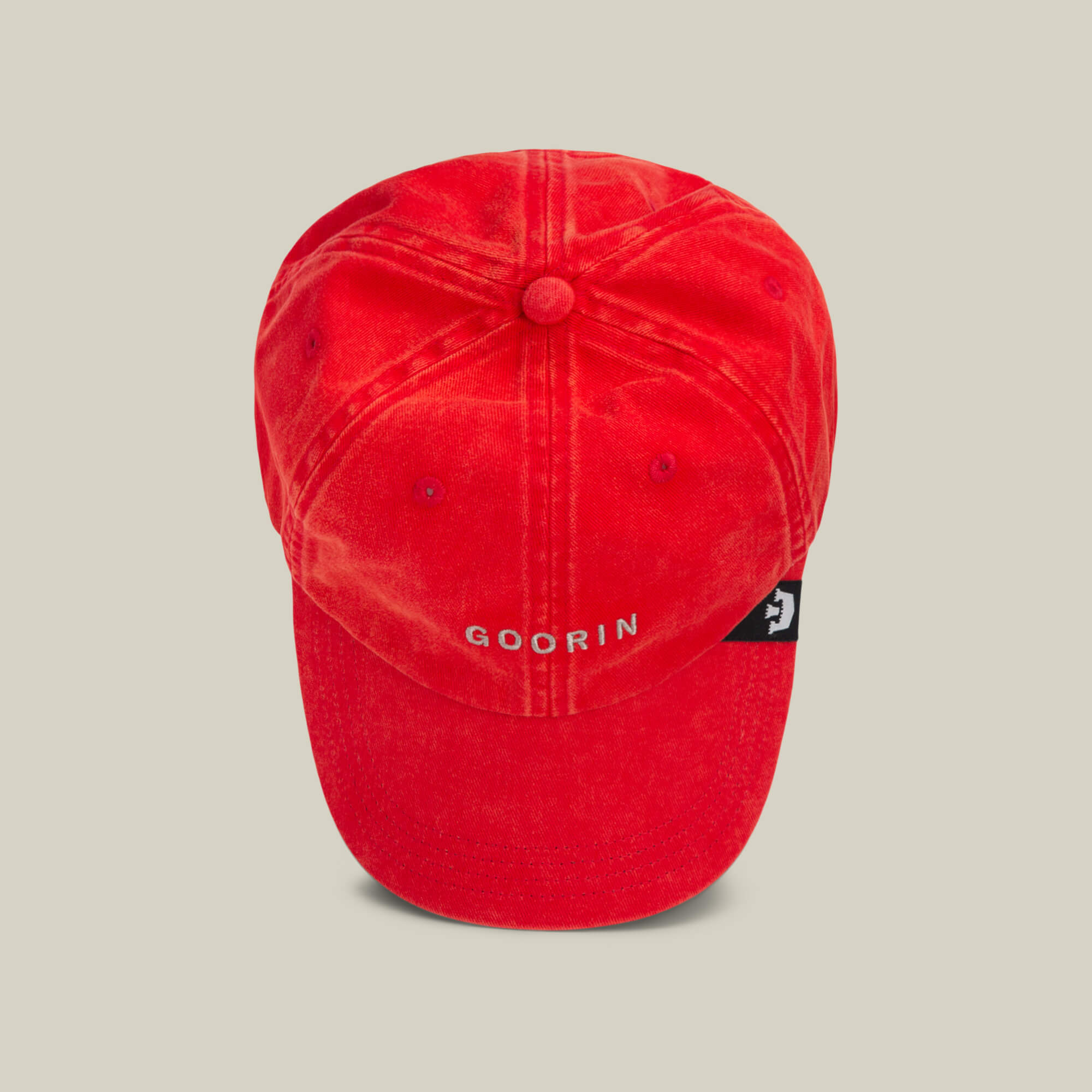 The Papa Cap Italiano by Goorin Bros. is a classic red baseball cap featuring bold white GOORIN text on the front and a navy tag with a white emblem on the side, shown against a beige background.