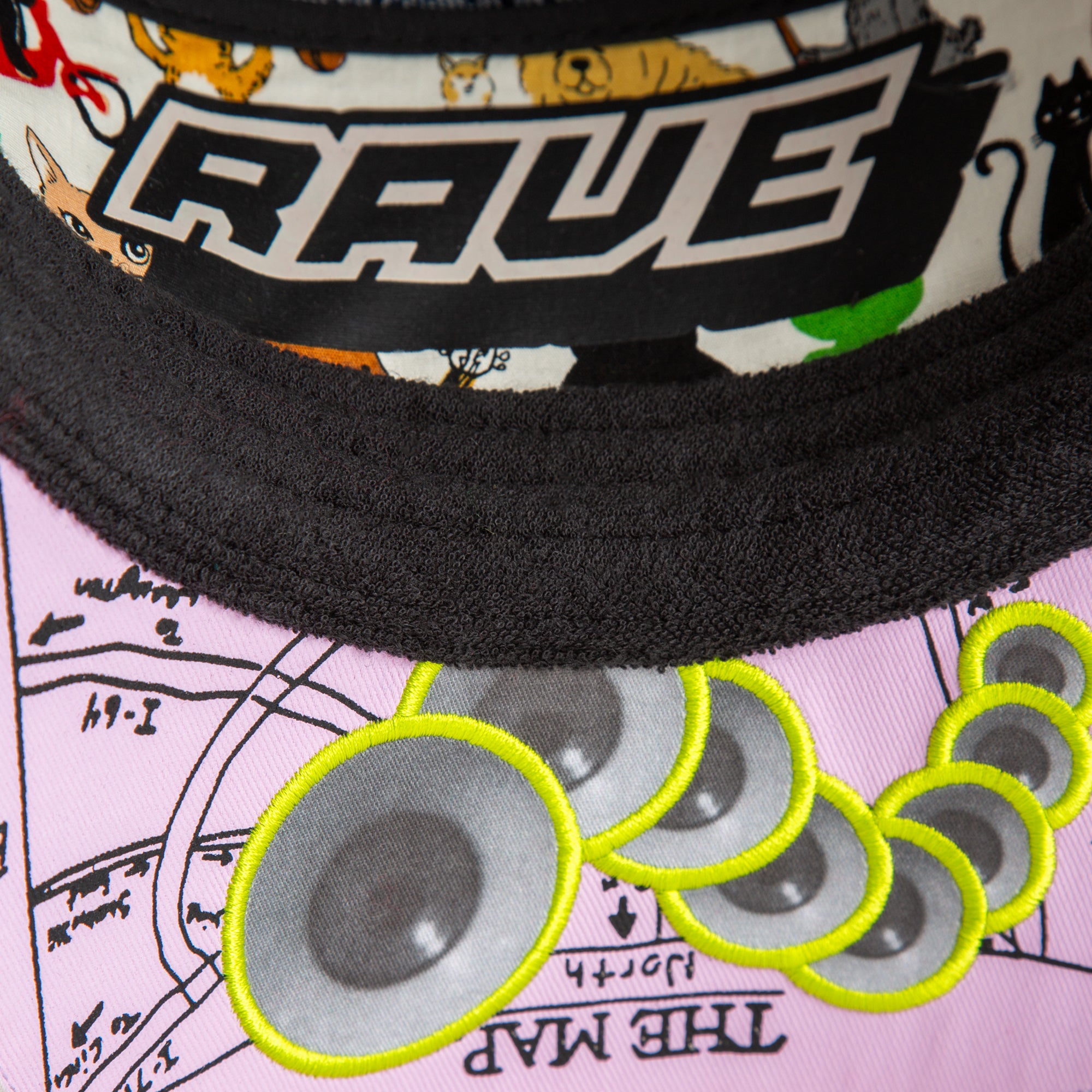Close-up of Goorin Bros.’ Trance hat, featuring RAVE lettering, illustrated animals, and embroidered speakers on pink fabric labeled THE MAP—a standout festival accessory for fans living life at 128 BPM.