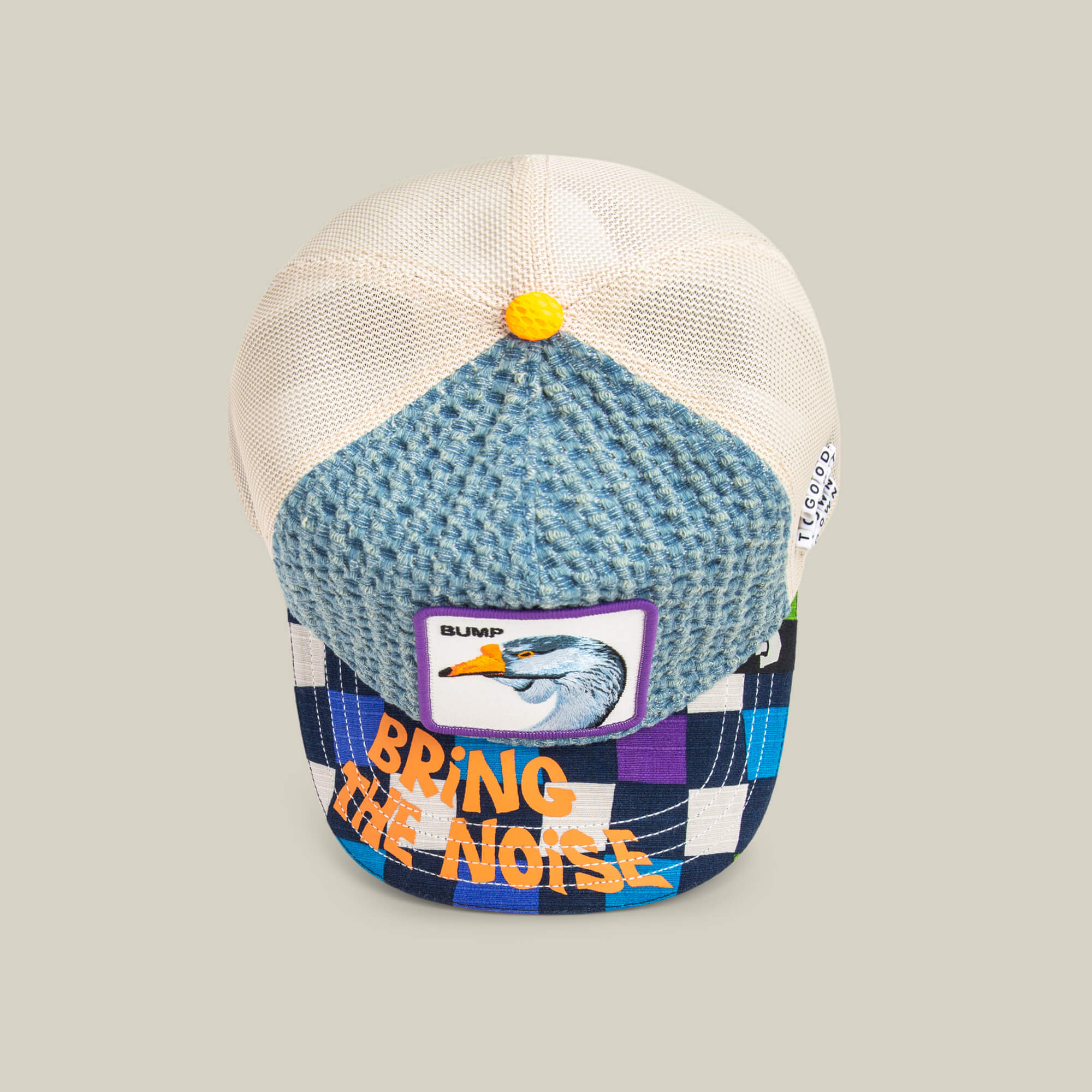 The “Acid House” trucker hat by Goorin Bros. features a blue textured front, mesh back, a bird patch with “BUMP,” and a checkered brim with “BRING THE NOISE”—ideal for Acid House fans heading to their next laser dome party.