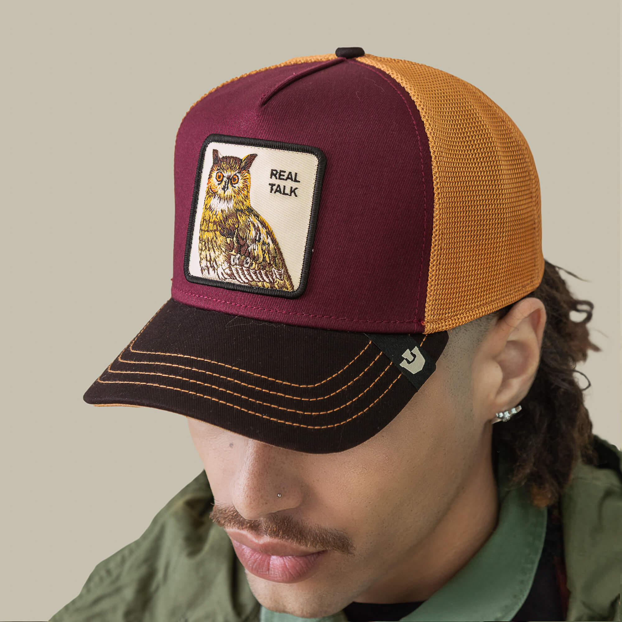 A person wearing the Goorin Bros. Tricolor Owl cap with an orange honey mesh design and an owl patch reading "REAL TALK," viewed from above and slightly to the side.