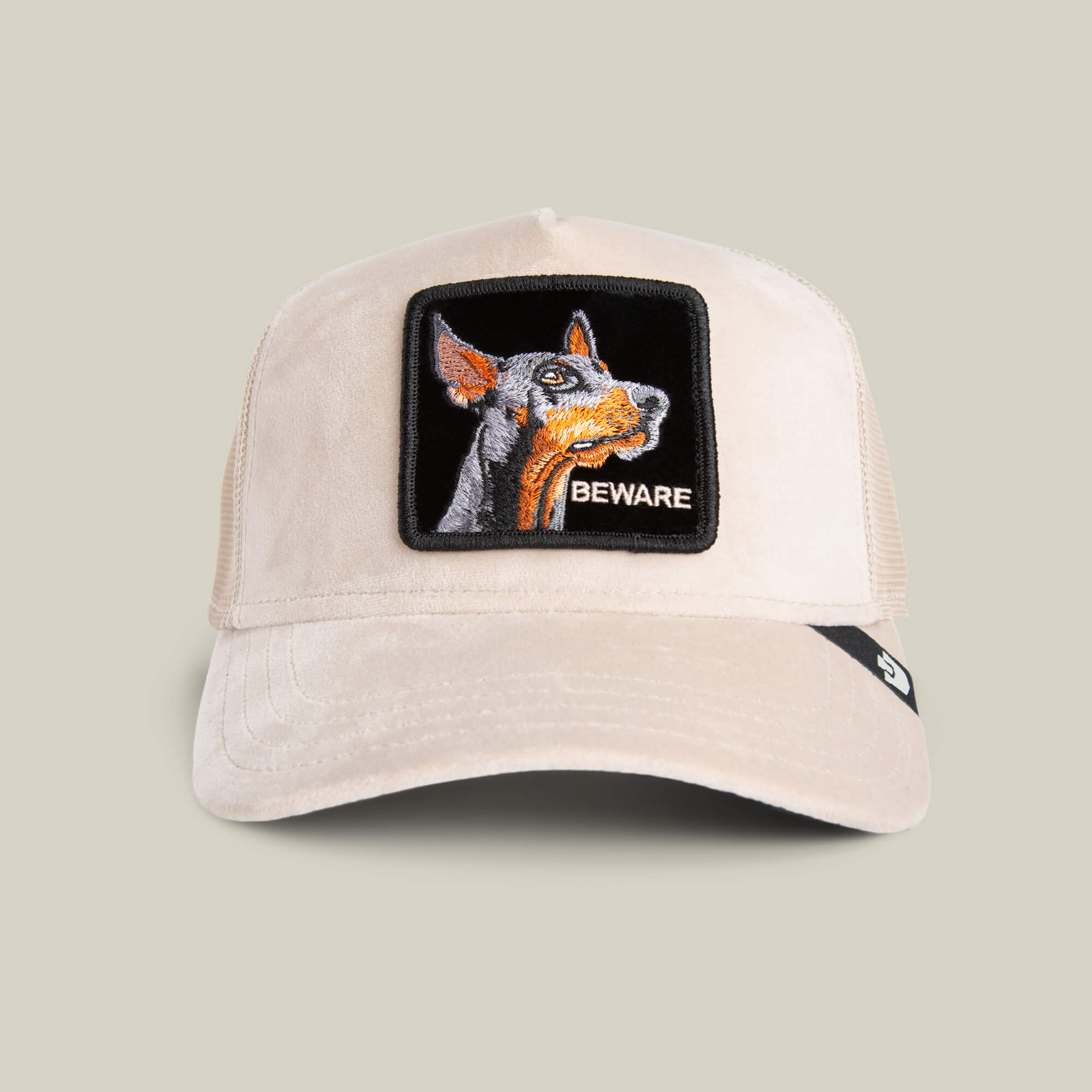 The Goorin Bros. Velour Doberman cap in BISCUIT features a mesh back, a playful Doberman patch, and "BEWARE" on the front—a luxury statement hat blending standout detail with style.
