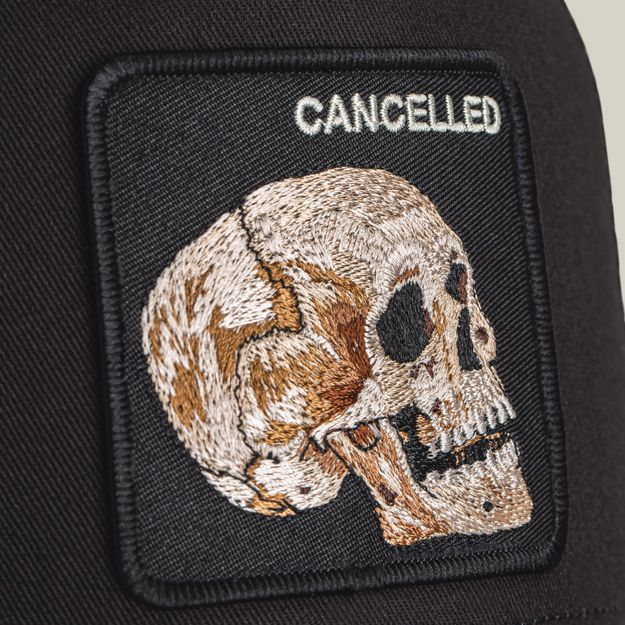 The Cancelled Skull by Goorin Bros. is an embroidered patch with a stitched skull in profile and the word "CANCELLED" above it, set on a black fabric background.