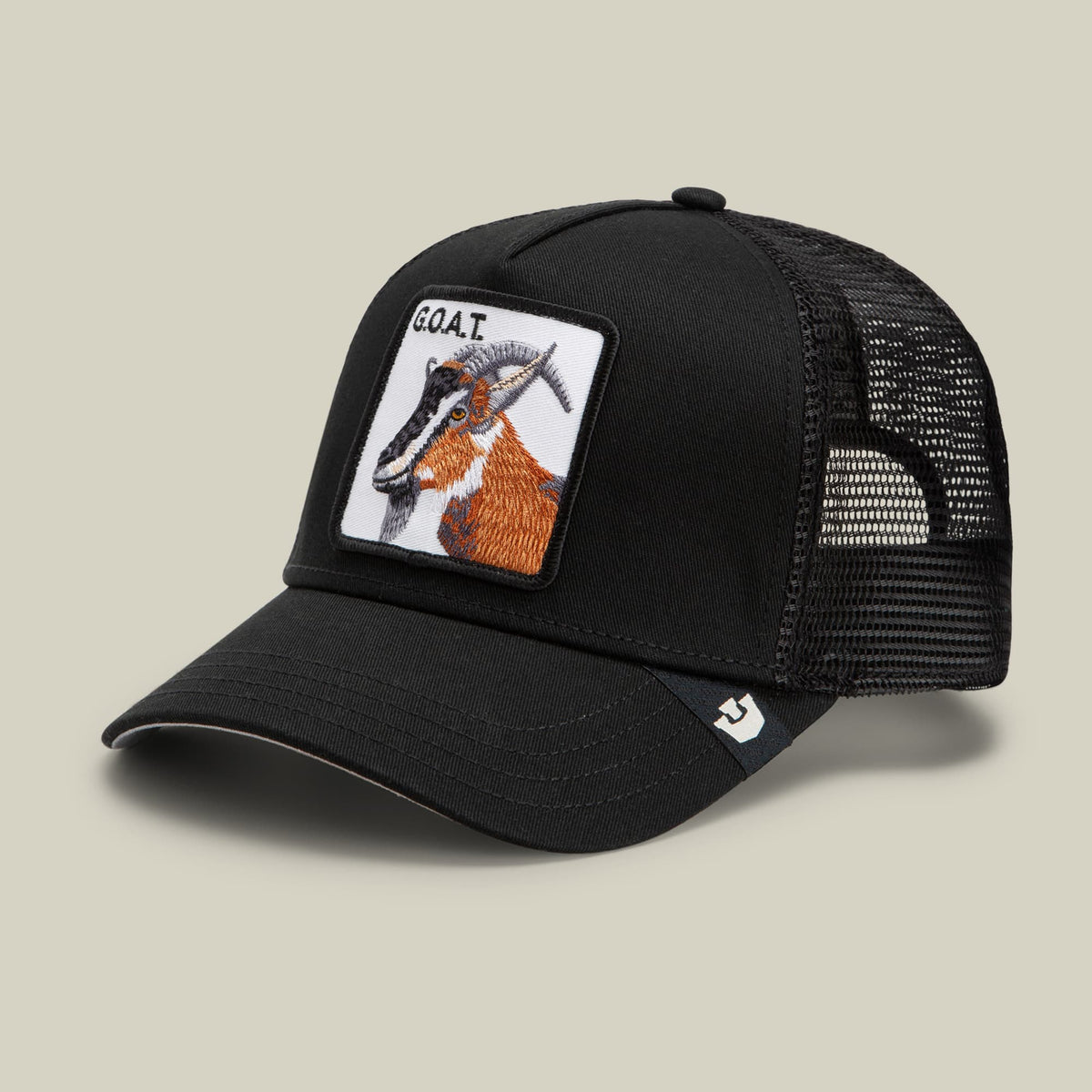 The Goorin Bros. Goat Trucker is a black mesh trucker hat featuring an embroidered goat patch with orange and white details on the front panel, displayed against a neutral background.