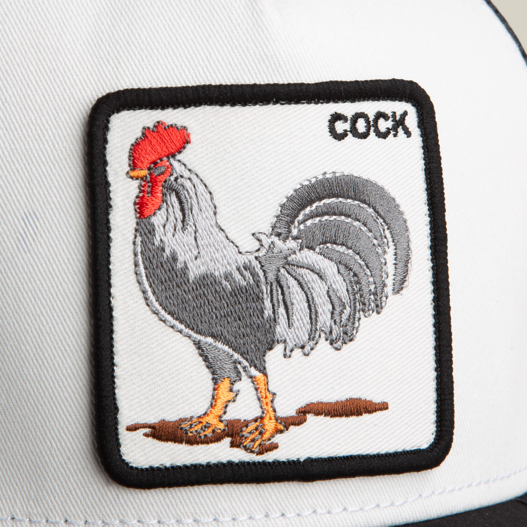 The Rooster by Goorin Bros. is a white trucker hat featuring a bold black and red rooster patch on the front.
