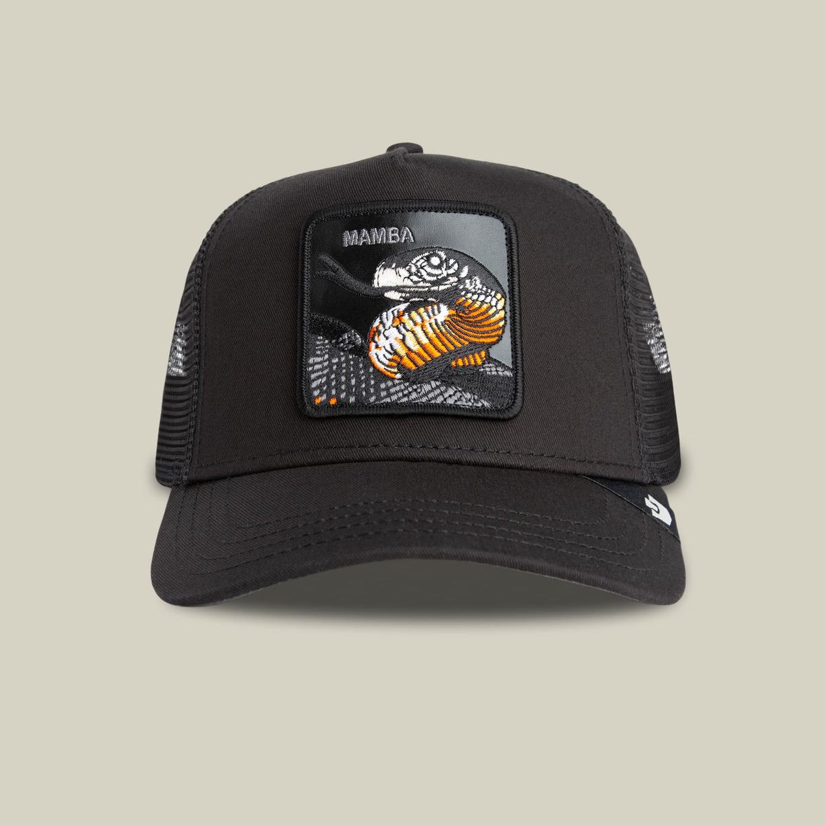 The Goorin Bros. Mamba Trucker is a black mesh trucker hat featuring a detailed front patch with an orange and black mamba snake graphic and text, displayed on a beige background.