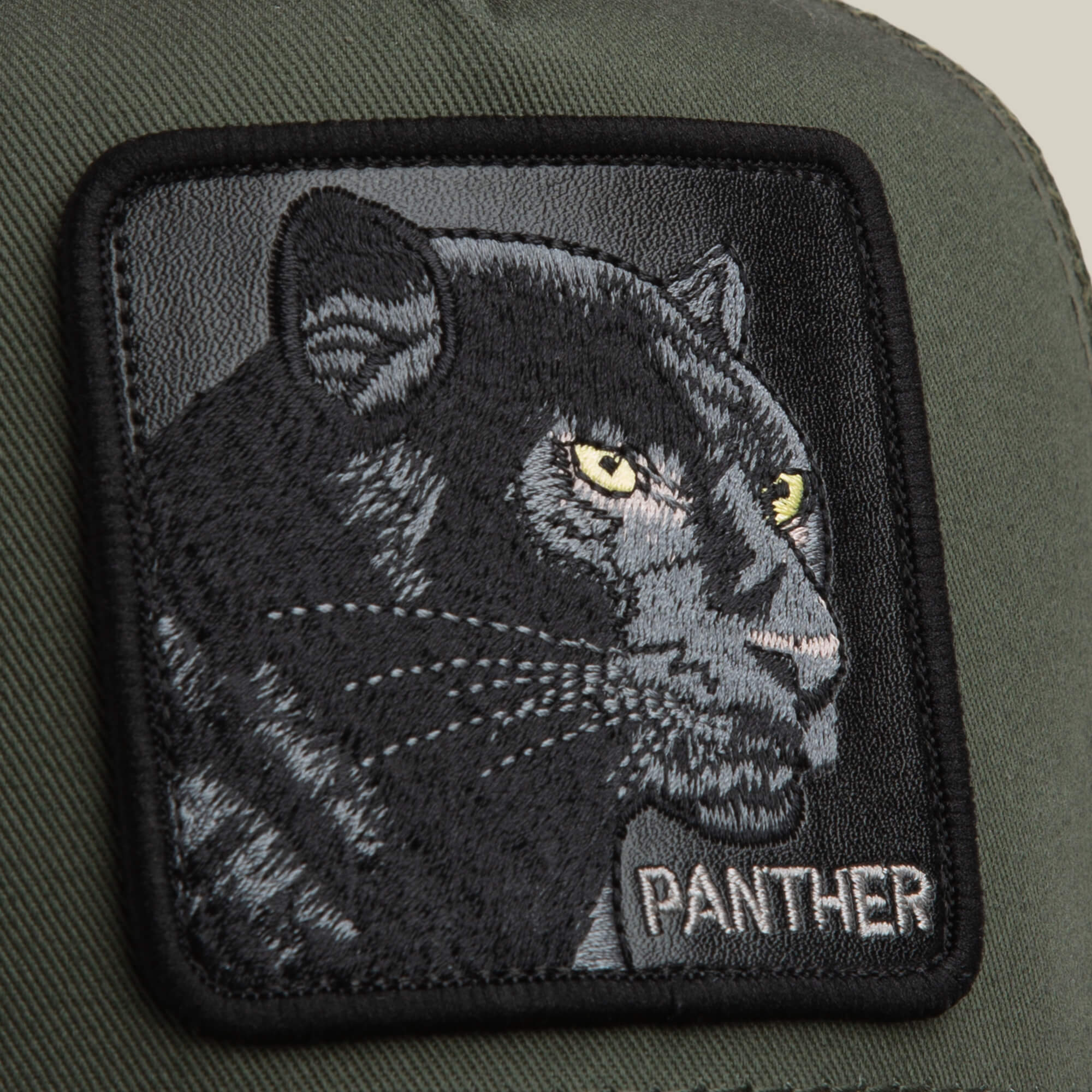 A close-up of The Panther patch by Goorin Bros.—a green fabric with an embroidered black panther, yellow eyes, and 'PANTHER' in white at the bottom right—perfect for bold style on your classic hat.