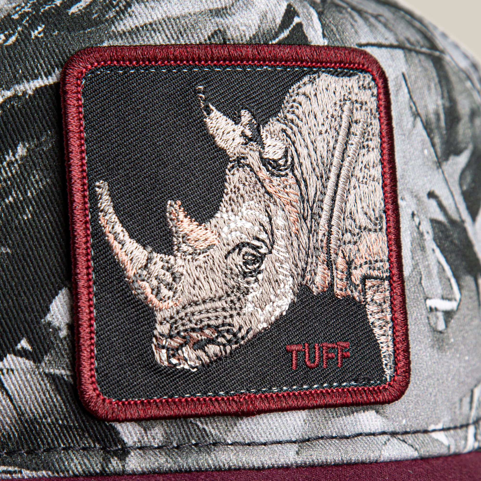 Close-up of a fabric patch on a low crown Goorin Bros. Tuff Camo hat, featuring an embroidered rhinoceros head and the word "TUFF" in red.