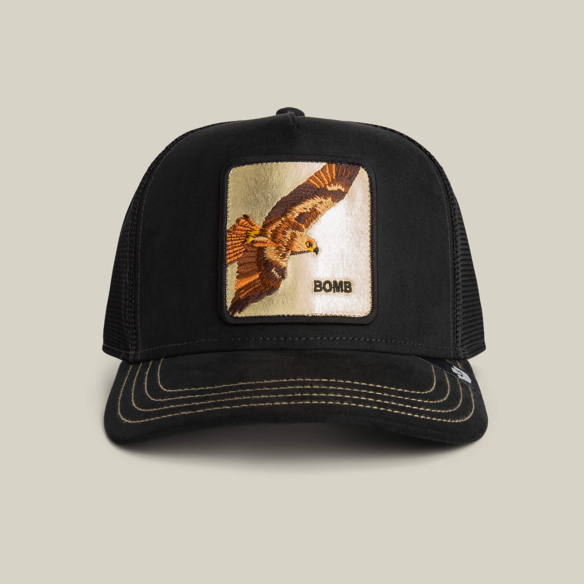 The Goorin Bros. Golden Bomb is a black trucker hat with a mesh back, featuring a front square patch of an embroidered bird in flight and the words "Golden Bomb"—rise high in style.