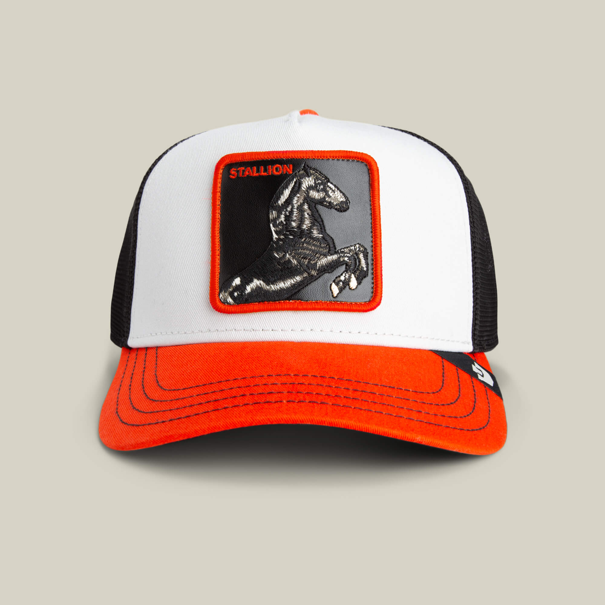 The Tricolor Stallion by Goorin Bros. is a white and black mesh trucker hat with a bright orange visor, featuring an embroidered stallion patch above the STALLION label on the front.