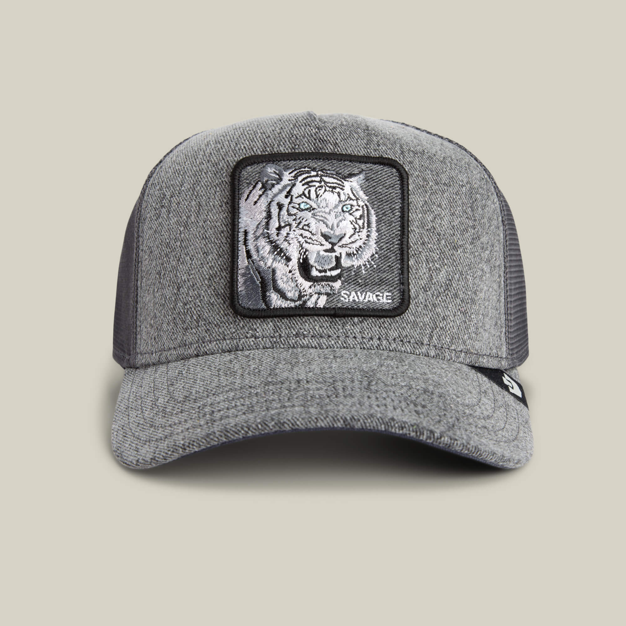 The Goorin Bros. Denim Savage hat is a gray trucker cap with mesh back and a front patch showing bold tiger embroidery and "SAVAGE" in white—an eye-catching streetwear accessory.