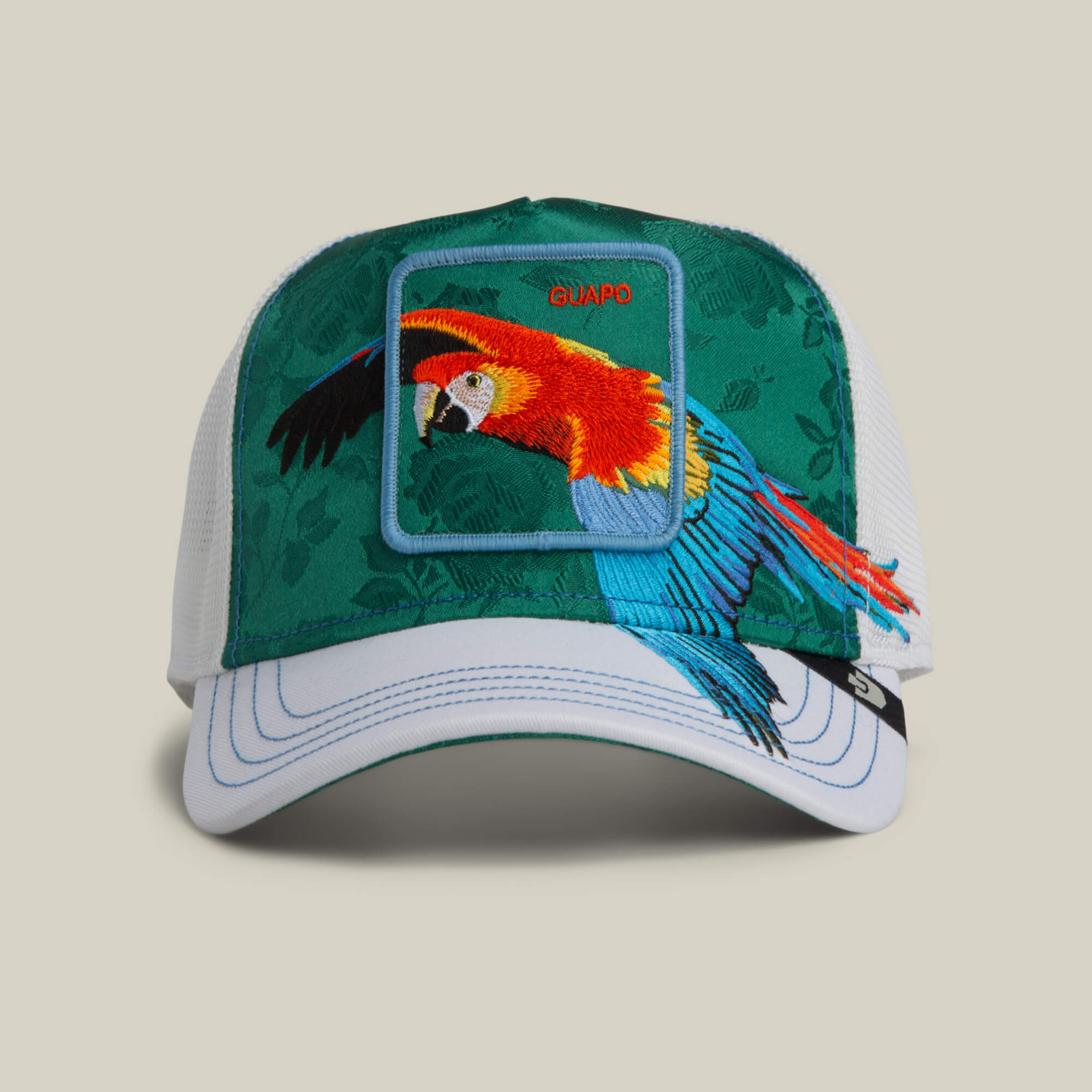 The Goorin Bros. Honduras Macaw cap features a vibrant embroidered tropical macaw patch and "GUAPO" on the front panel.