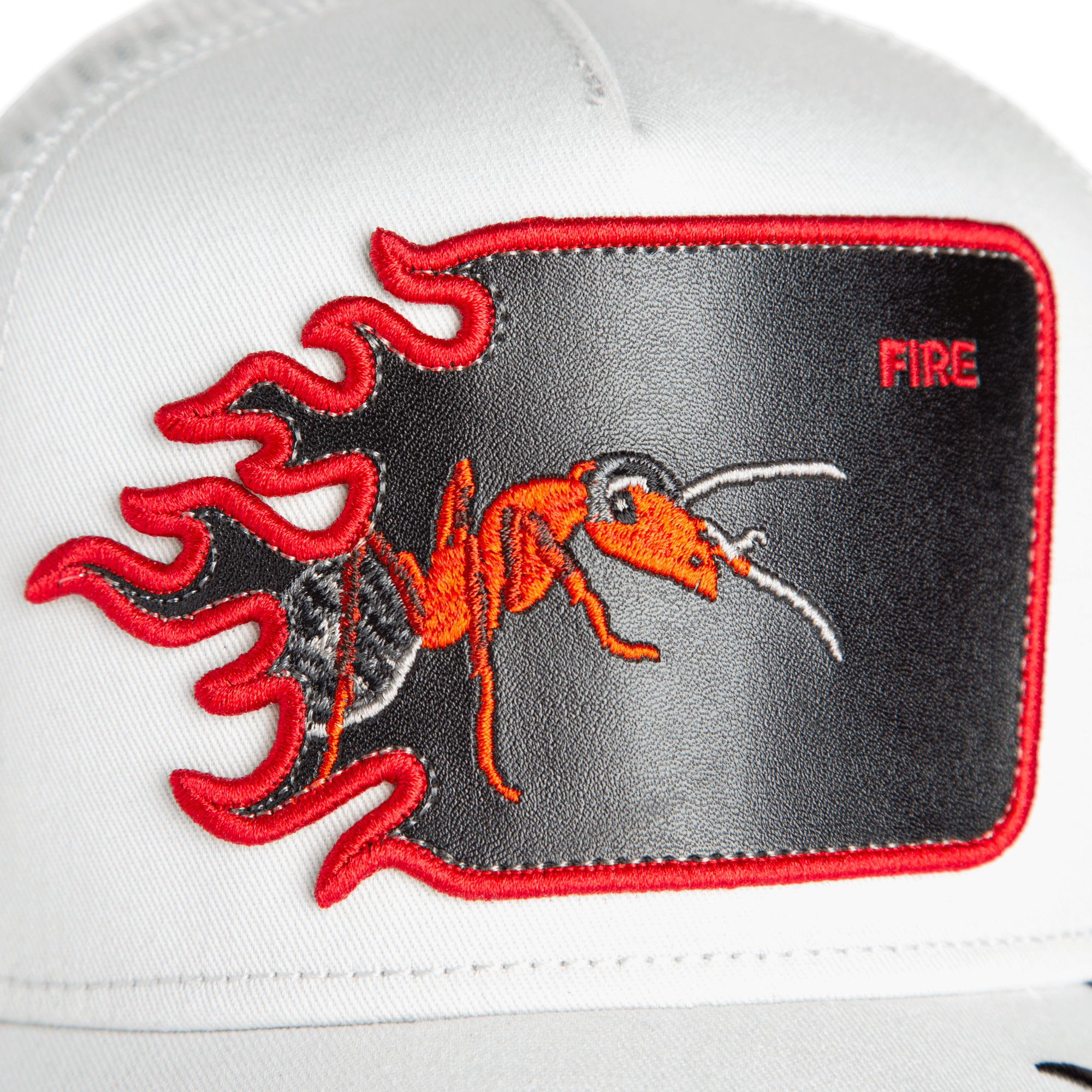 The Goorin Bros. Fire Flames trucker hat is white with a red ant patch, embroidered fire flames, and the word "FIRE" in the top right corner.