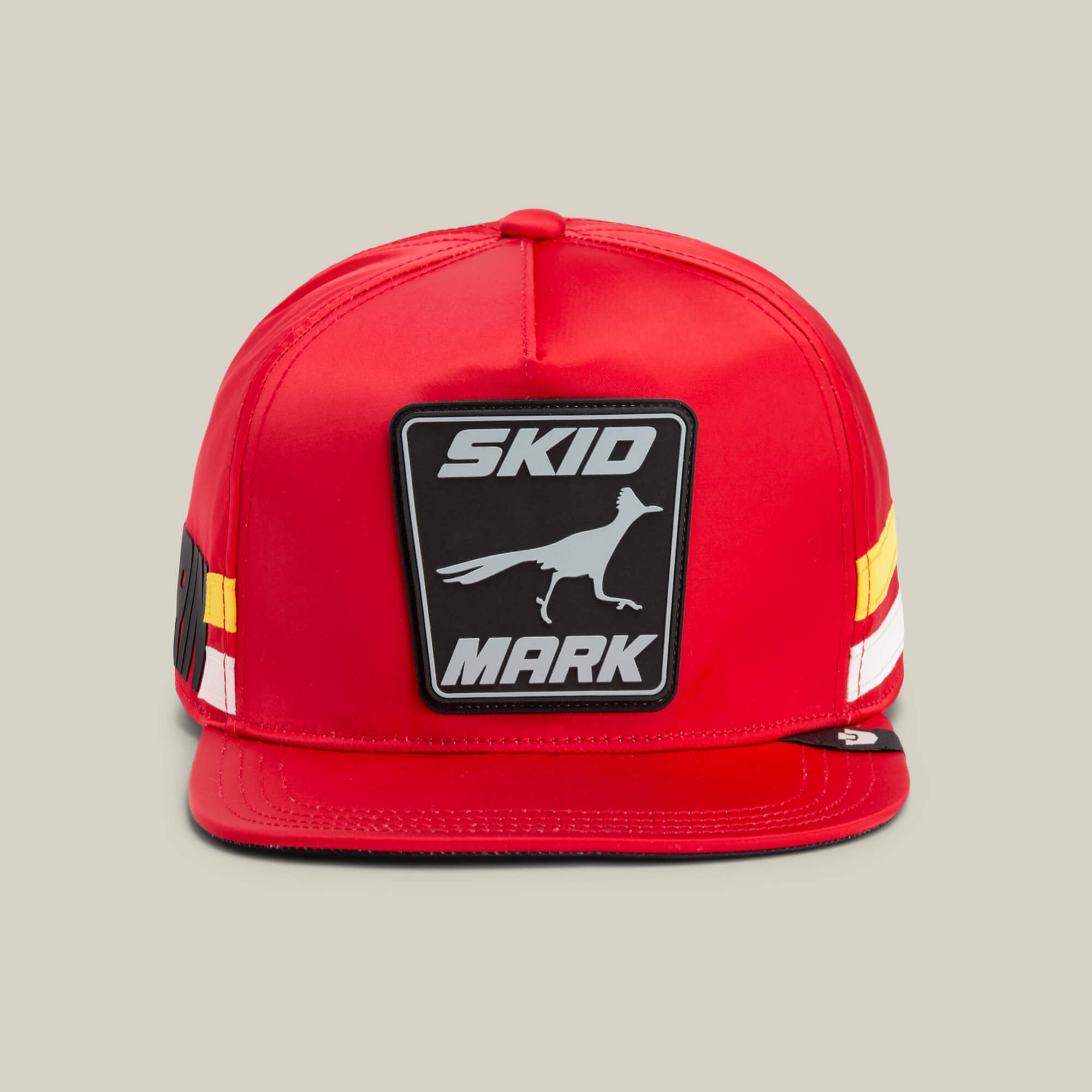 The Goorin Bros. Pole Position - Skid Mark snapback features a RUSH hue with white and yellow stripes, plus a running bird patch evoking roadrunner speed and bold SKID MARK text on the front.