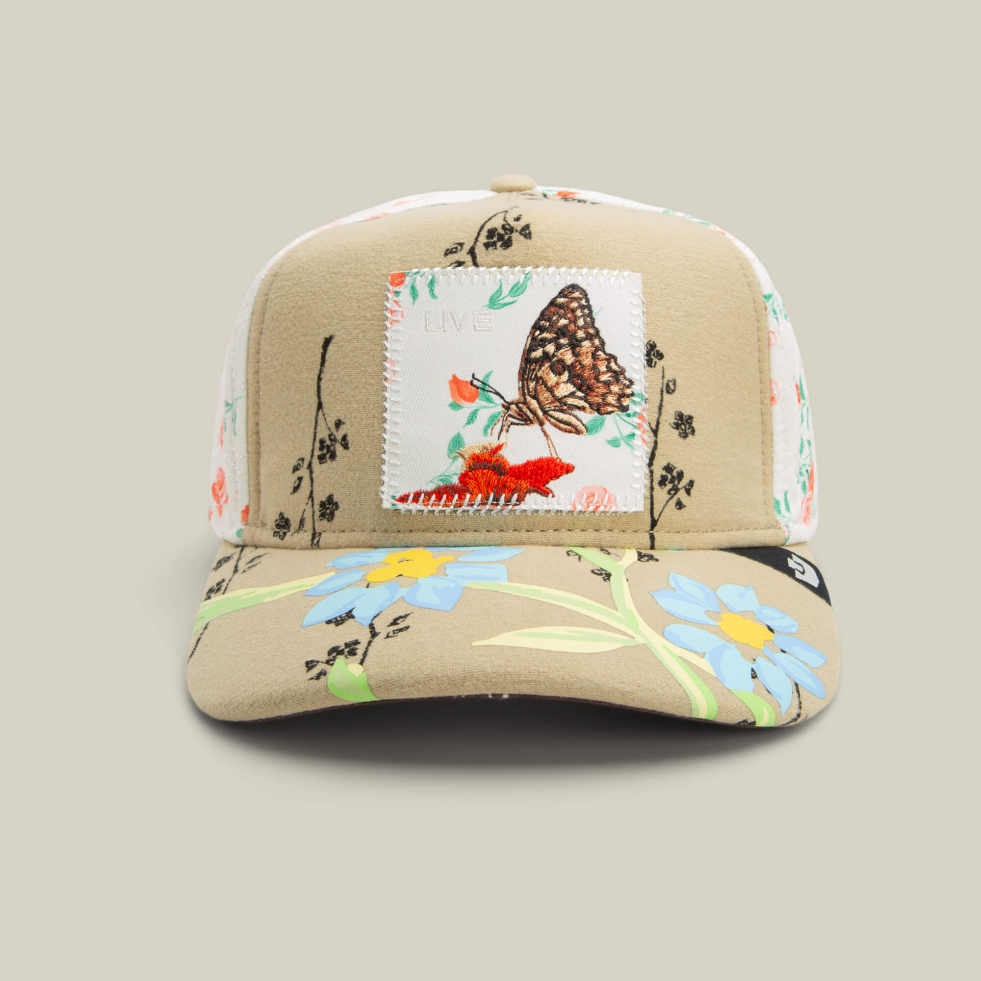 The Vol. 1 - Quiltbag: Live hat by Goorin Bros. in SCOUT features blue and orange floral embroidery and a bold butterfly patch on the front panel.