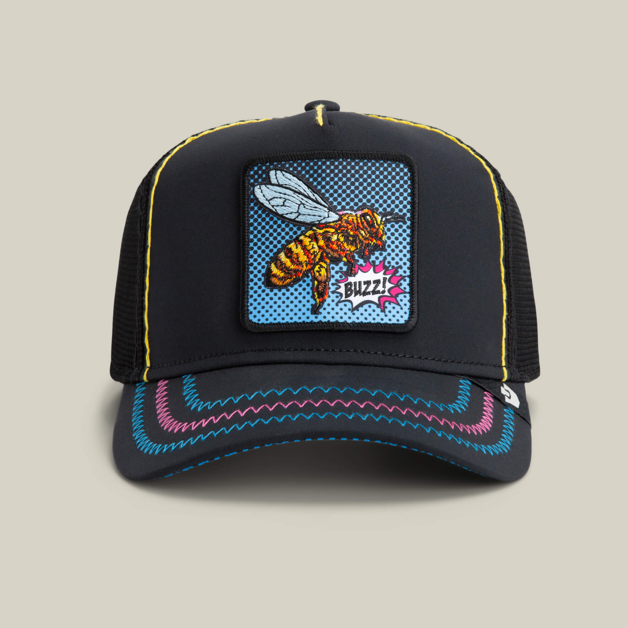 The Goorin Bros. Oh Bee Hive hat in VOID color features black mesh, a pop-art bee patch with "Buzz!", colorful brim stitching, and yellow crown accents.