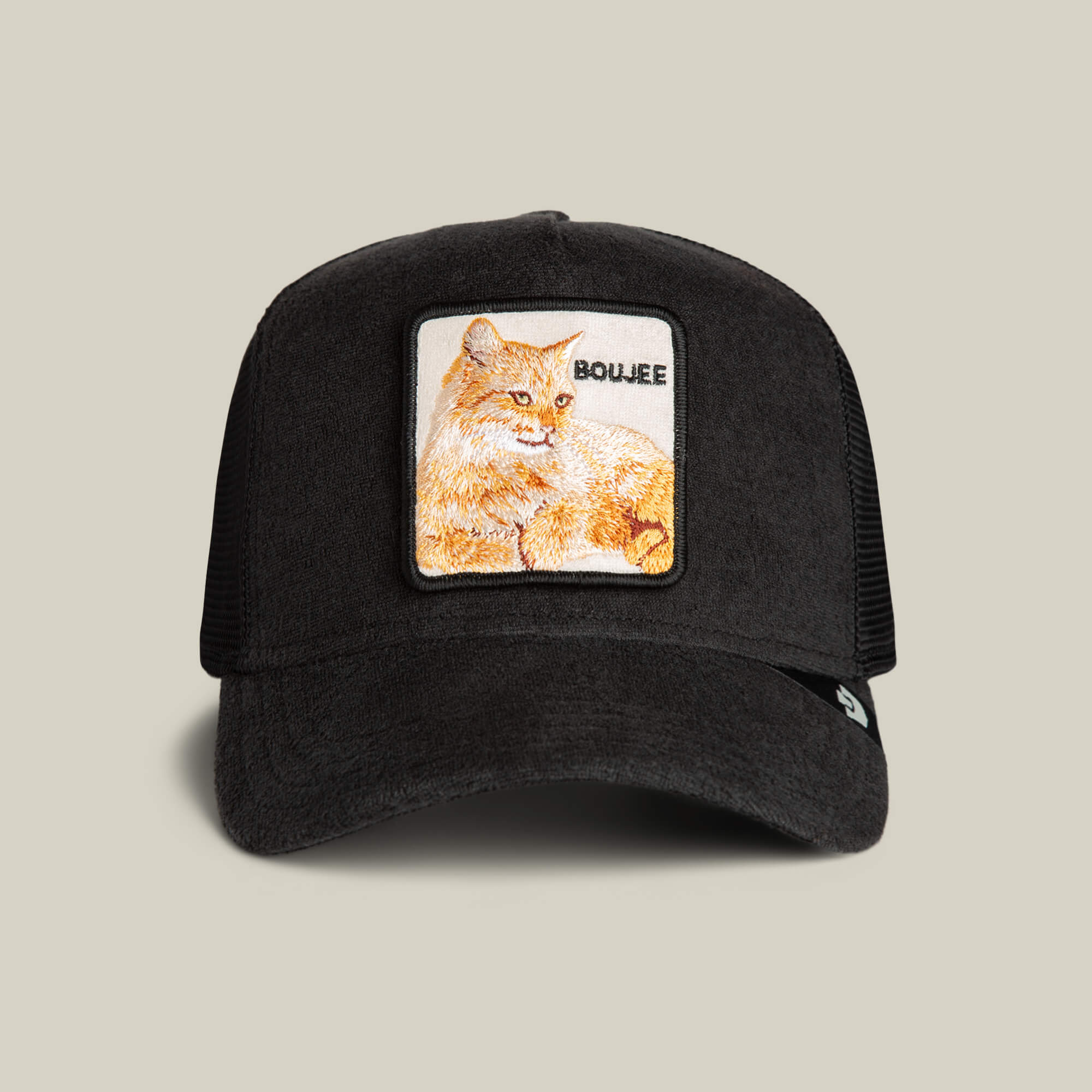 The Goorin Bros. Terry Cloth Cat trucker hat in VOID features a square patch with an embroidered orange cat and "BOUJEE" on the front, blending luxe loungewear inspiration with plush comfort for a stylish vibe.