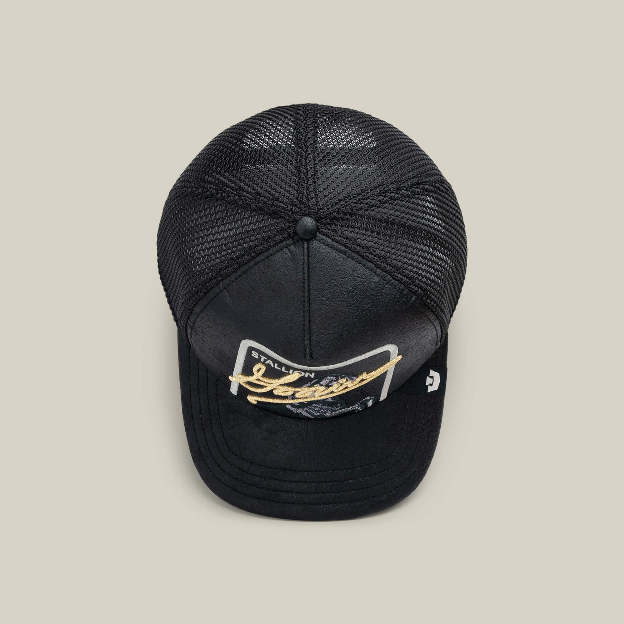 The NeoBrand STALLION by Goorin Bros. is a black mesh trucker hat with a curved bill, gold monochrome "STALLION Jeans" patch on the front—ideal for pairing with blacked-out sneakers.
