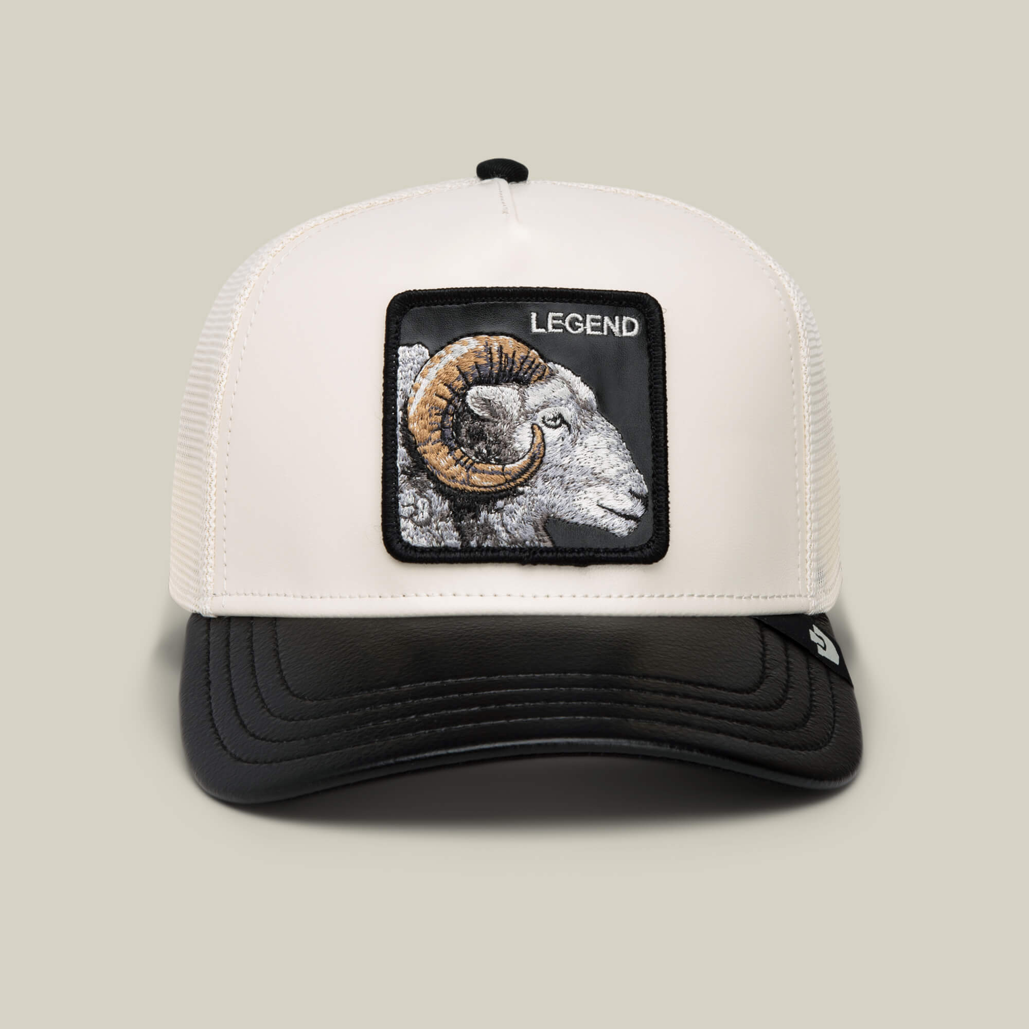 The Goorin Bros. Faux Leather Ram trucker hat in VOID/CHALK features a cream faux leather ram patch, “LEGEND” embroidery above it, and a classic black brim.