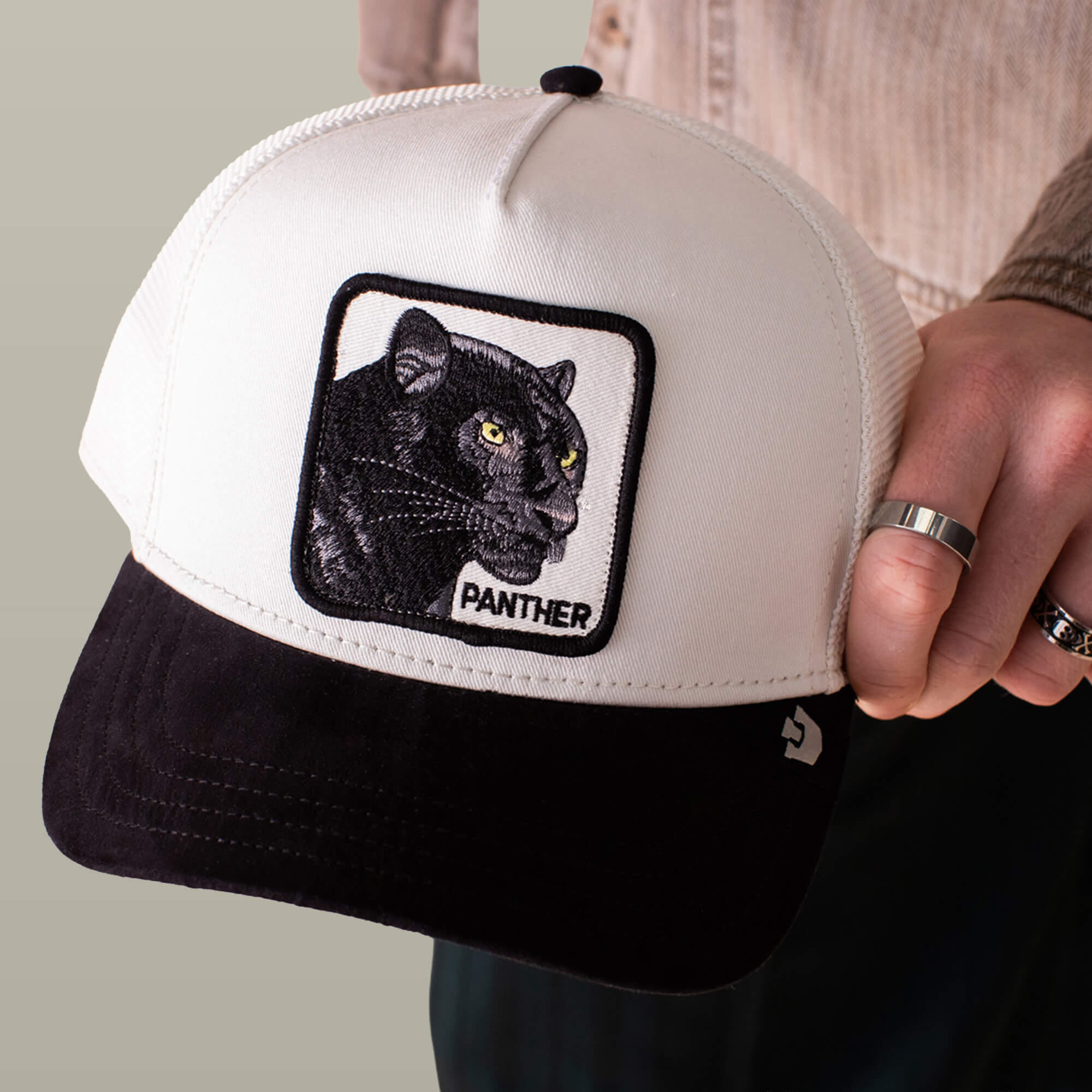 Someone holds the Goorin Bros. Suede Black Panther cap, which features a black and white panther patch, "PANTHER" embroidery below the image, and a sleek microsuede brim.