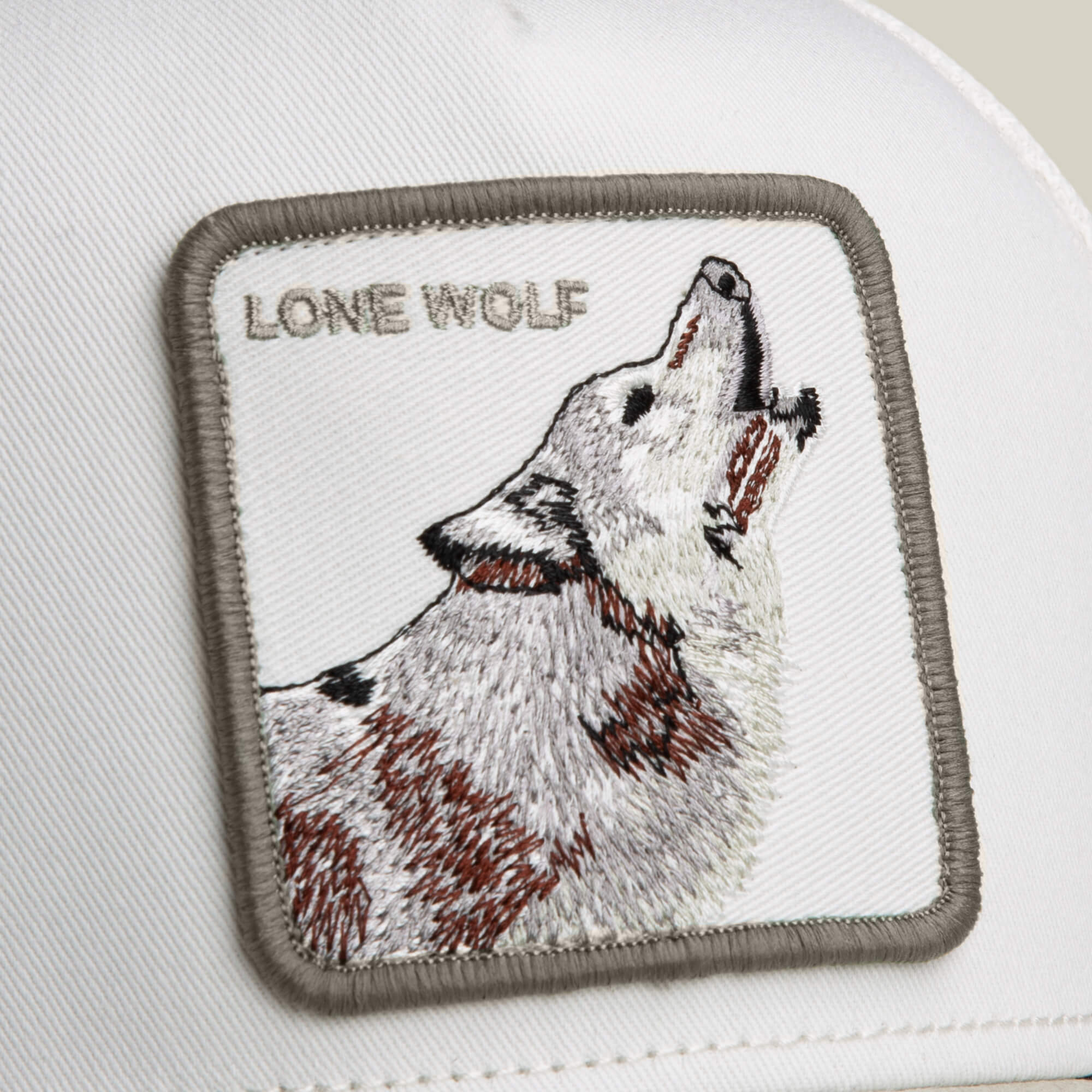 The Goorin Bros. Suede Wolf is a white cap with a suede brim, featuring a rectangular patch of a howling wolf and the words "LONE WOLF.
