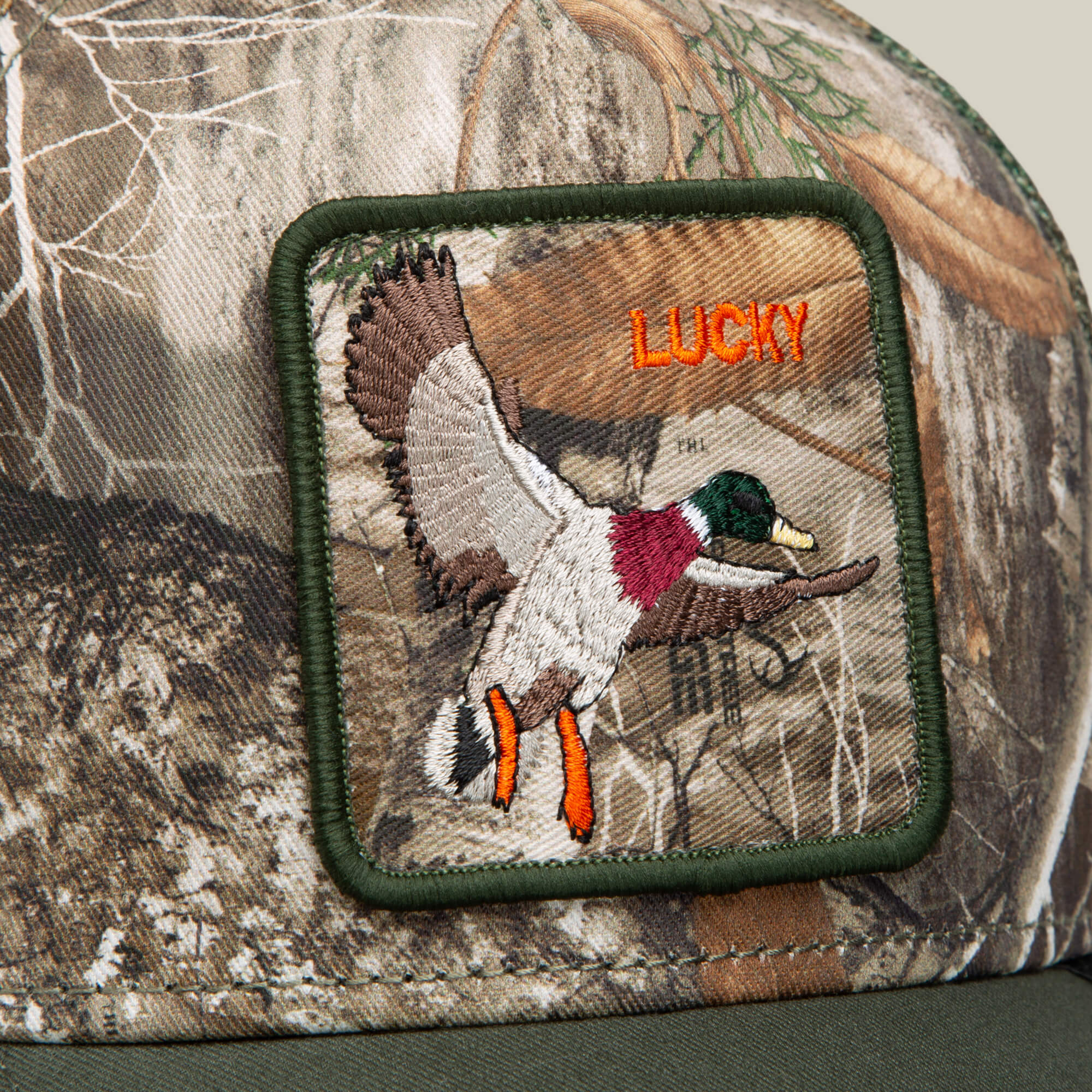 The Goorin Bros. Realtree Edge Lucky Duck cap features a camo pattern with a flying duck patch and "LUCKY" in bold orange letters.