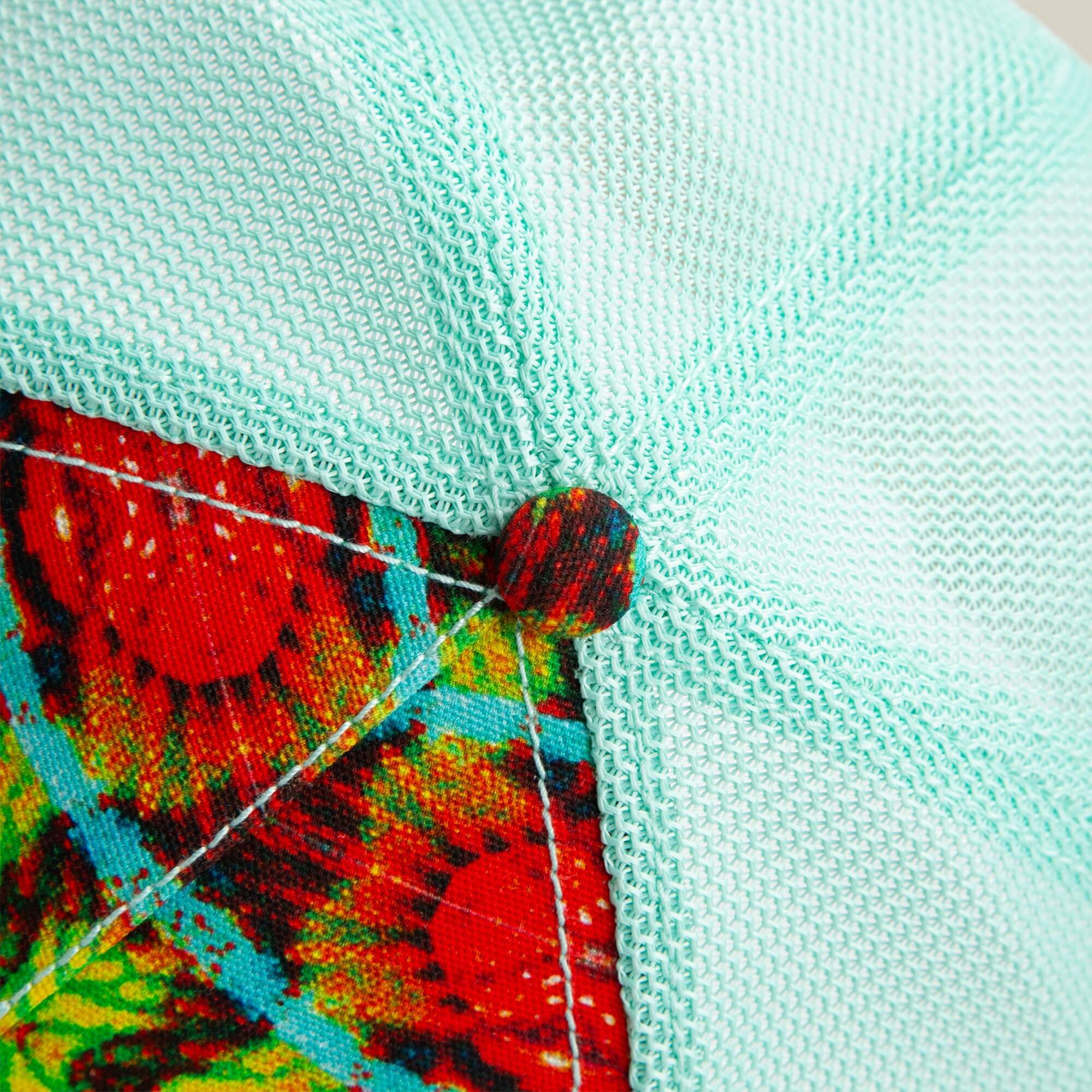 Close-up of the Goorin Bros. Magic Eye hat, featuring textured light blue mesh, a colorful button, and patterned seam accents that create subtle optical illusions.