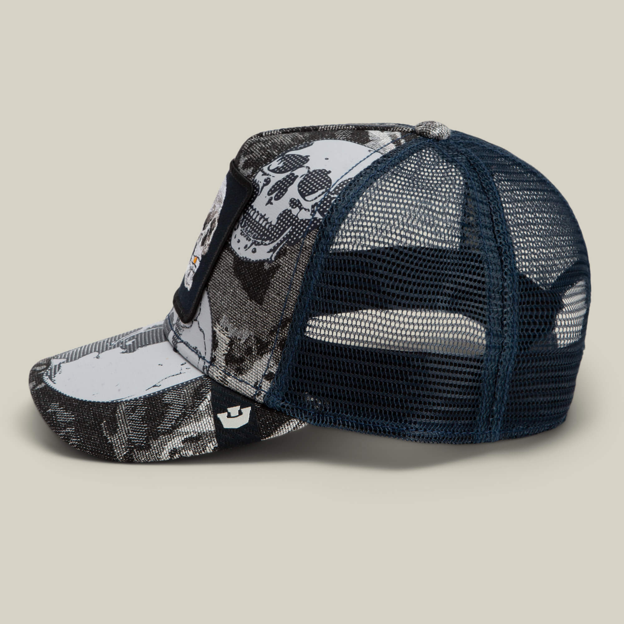 A side view of the Goorin Bros. Bone Head Danger trucker cap, featuring a bold black and white embroidered skull graphic, mesh back panels, and a curved brim, displayed against a neutral background.