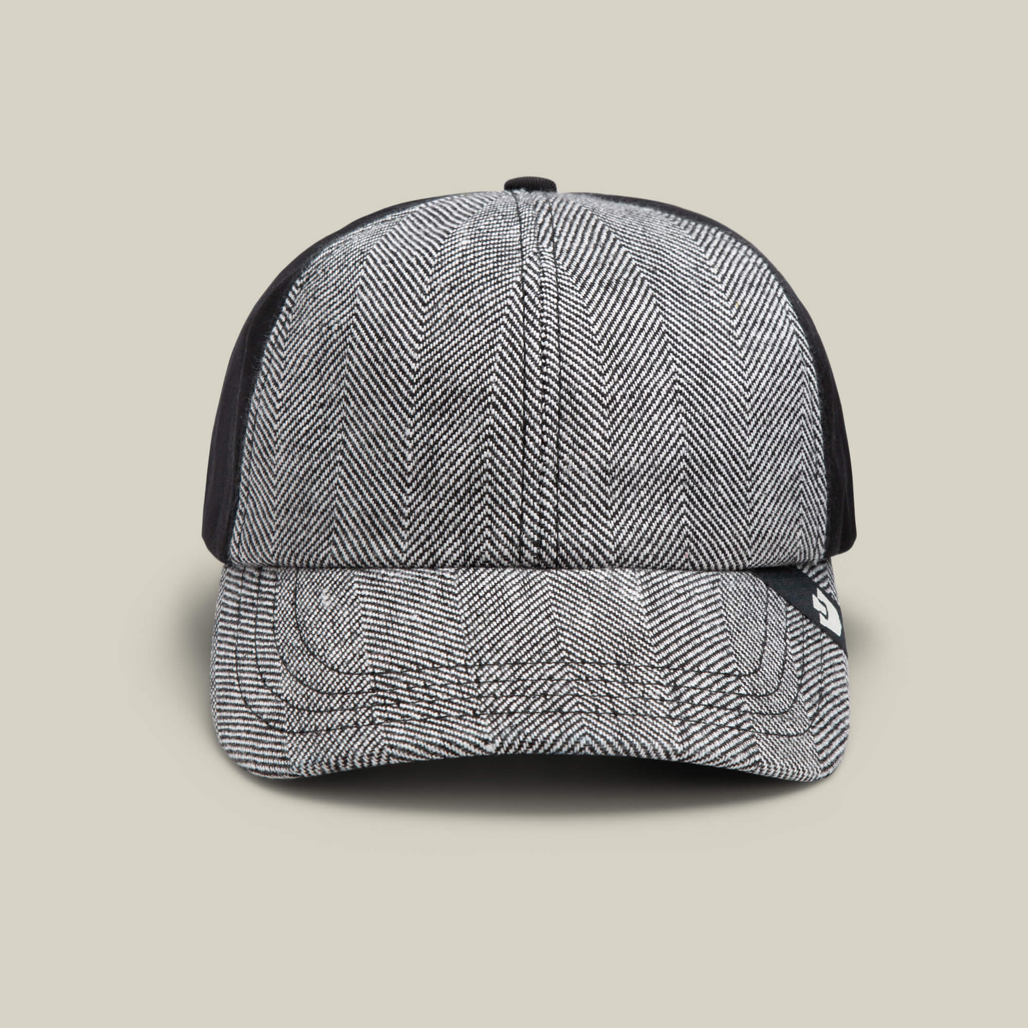 Front view of the Goorin Bros. Zig Zag Tailored Baseball cap in VOID, featuring a black and white herringbone pattern with solid black side panels, displayed against a plain beige background.