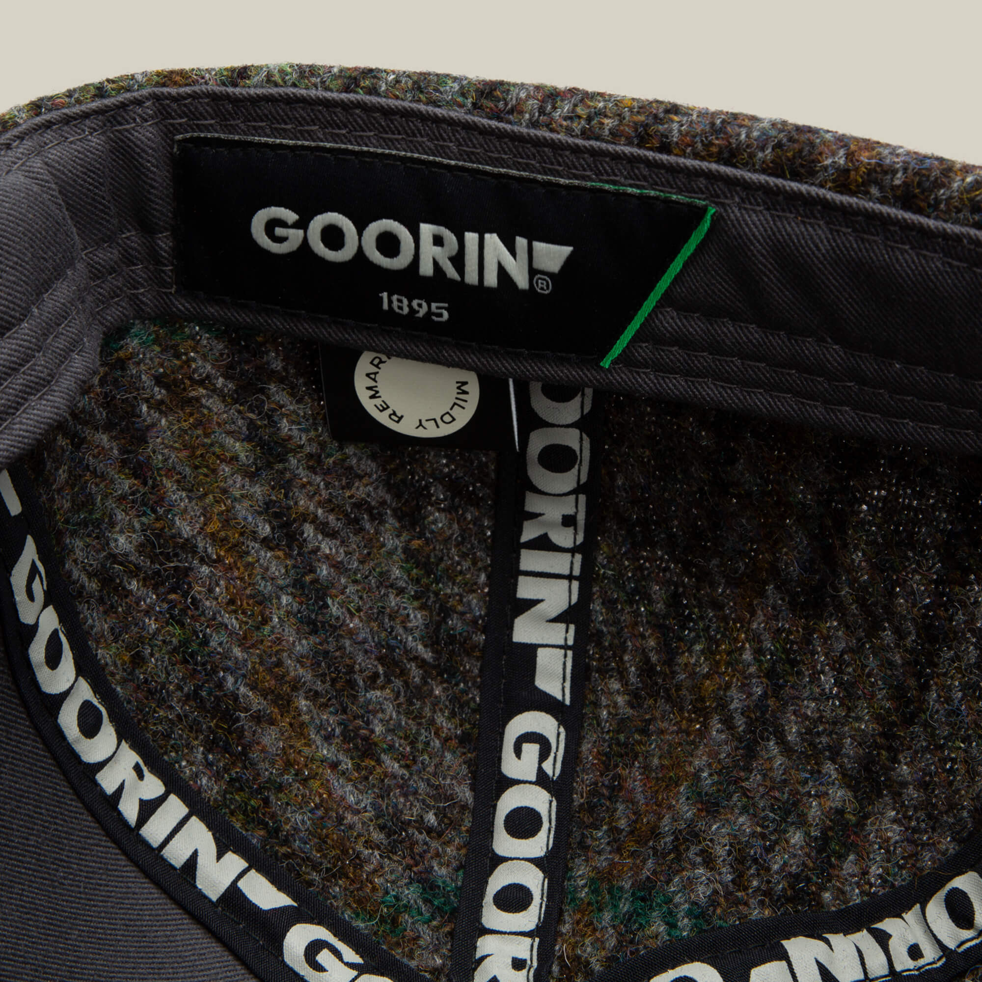 Close-up of the inside of a Goorin Bros. Cozy Tailored Baseball hat, showing the brand label and patterned inner lining with repeating GOORIN text on the hat band in a muted colorway.