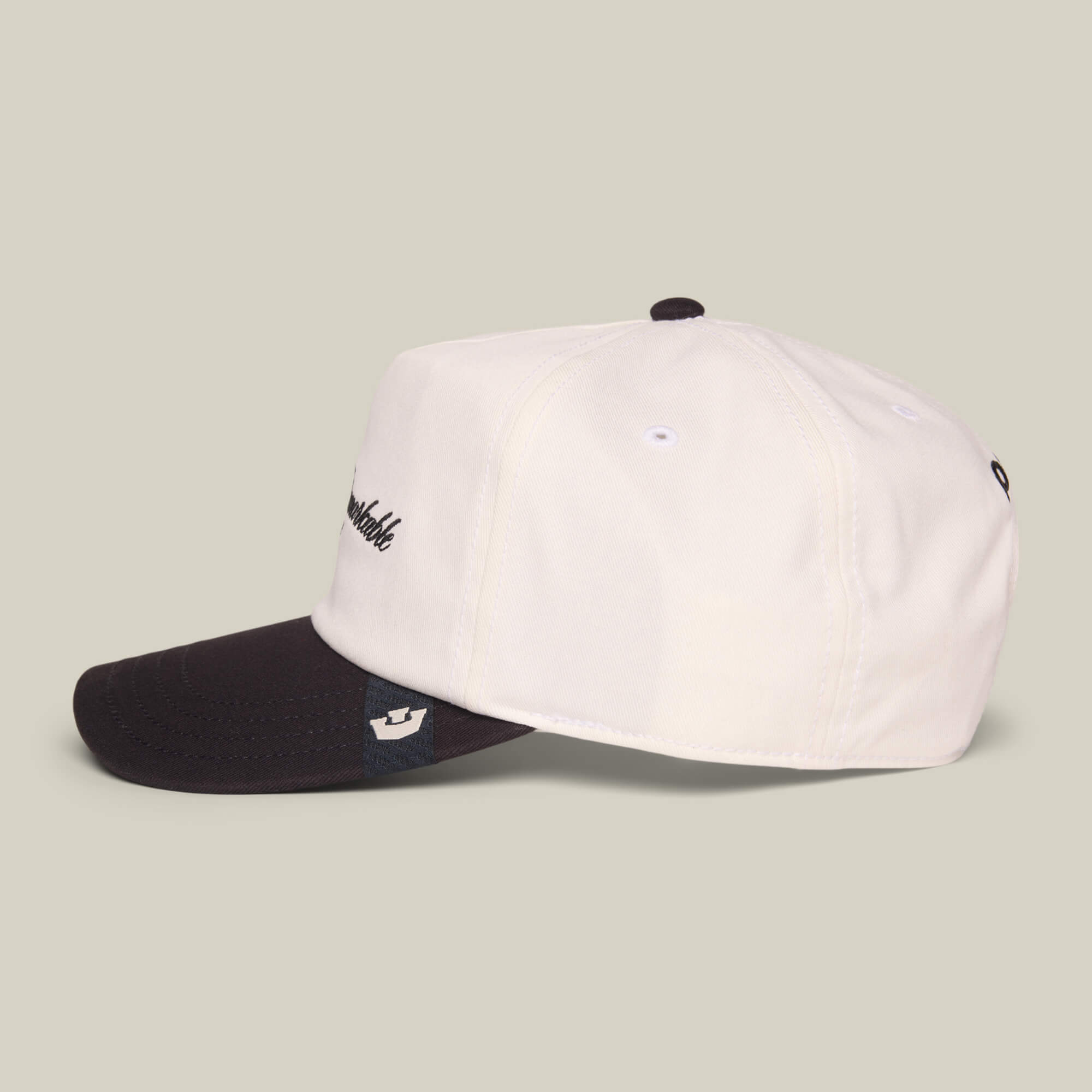 The Goorin Bros. Mildly Remarkable Script hat features a white crown, black brim, and classic script embroidery on the front, shown against a neutral background.