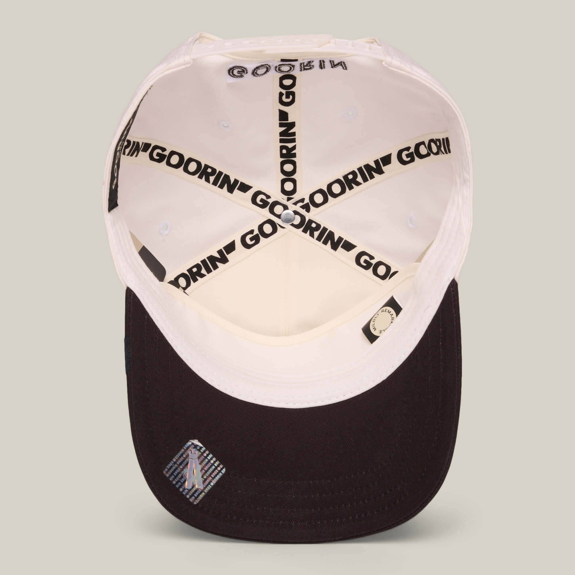 An inside view of the white and black Goorin Bros. Mildly Remarkable Script hat, featuring GOORIN branding on the inner seams, script embroidery, and a small label under the brim.