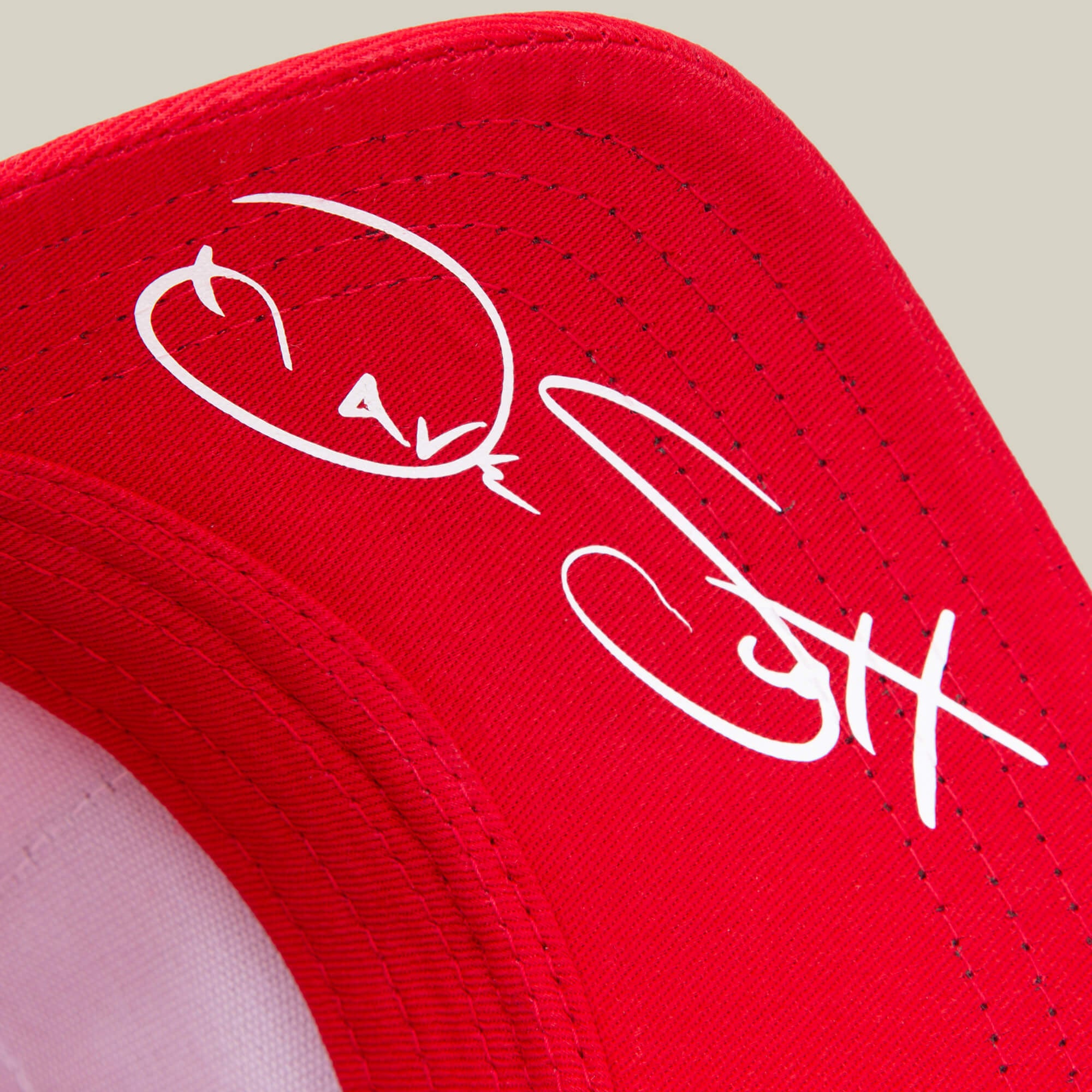 A close-up of the red Dave Scott Boom Goat hat by Goorin Bros., featuring a white autograph on the underside of the brim, as a tribute to a true GOAT legend.