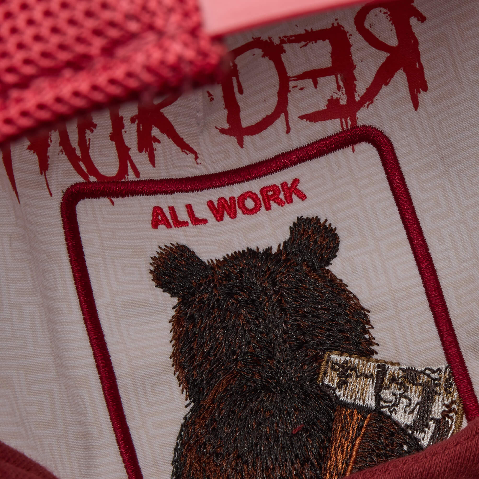 Close-up of Goorin Bros.' Dull Boi patch: an embroidered bear inspired by Johnny, with “ALL WORK” above and “MURDER” in red on top. The bear rests an axe on its shoulder—part of our All Work and No Play Fresh Friday Drop.