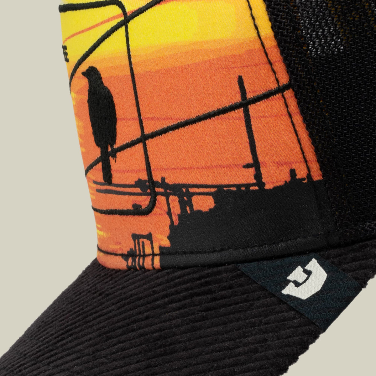It Was The Hat beanie by Goorin Bros features a yellow-to-orange gradient with black silhouettes of a bird on power lines against a sunset backdrop, paired with a black ribbed cuff and brand patch.