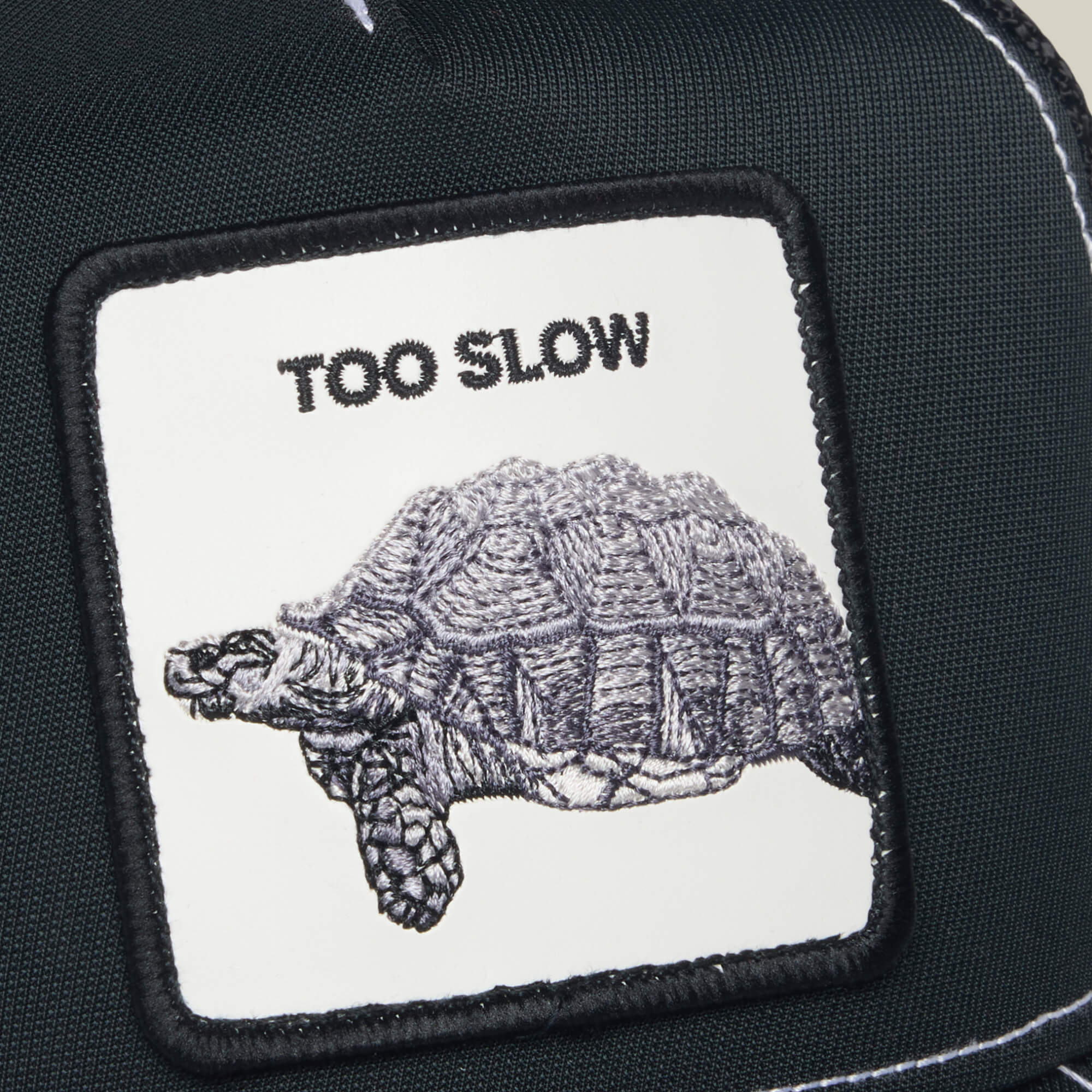 The Down Low... patch by Goorin Bros. features an embroidered tortoise with "TOO SLOW" stitched above it on fabric.