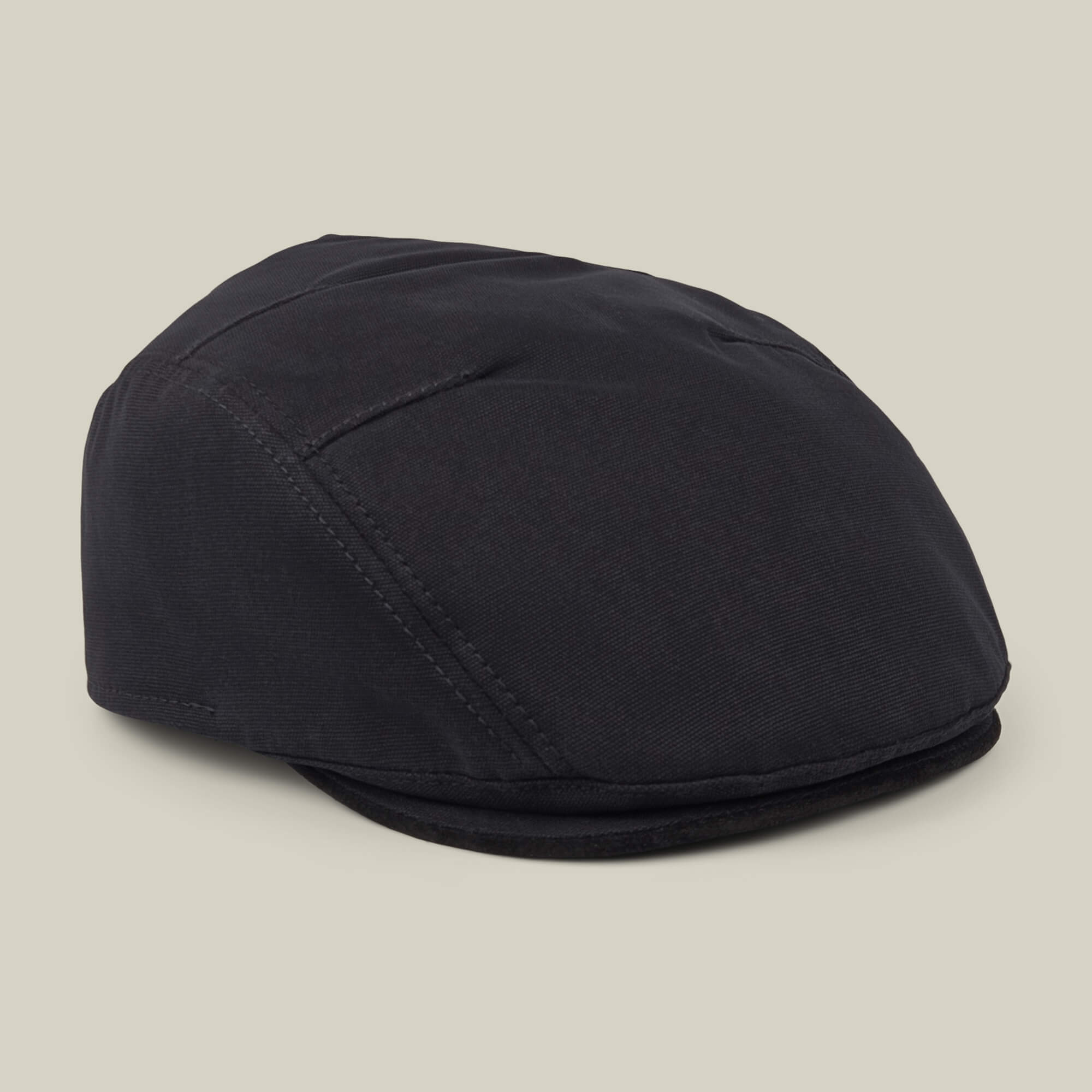 The Heatherwood flatcap by Goorin Bros., crafted from black cotton suede in the USA, is shown against a plain beige background.