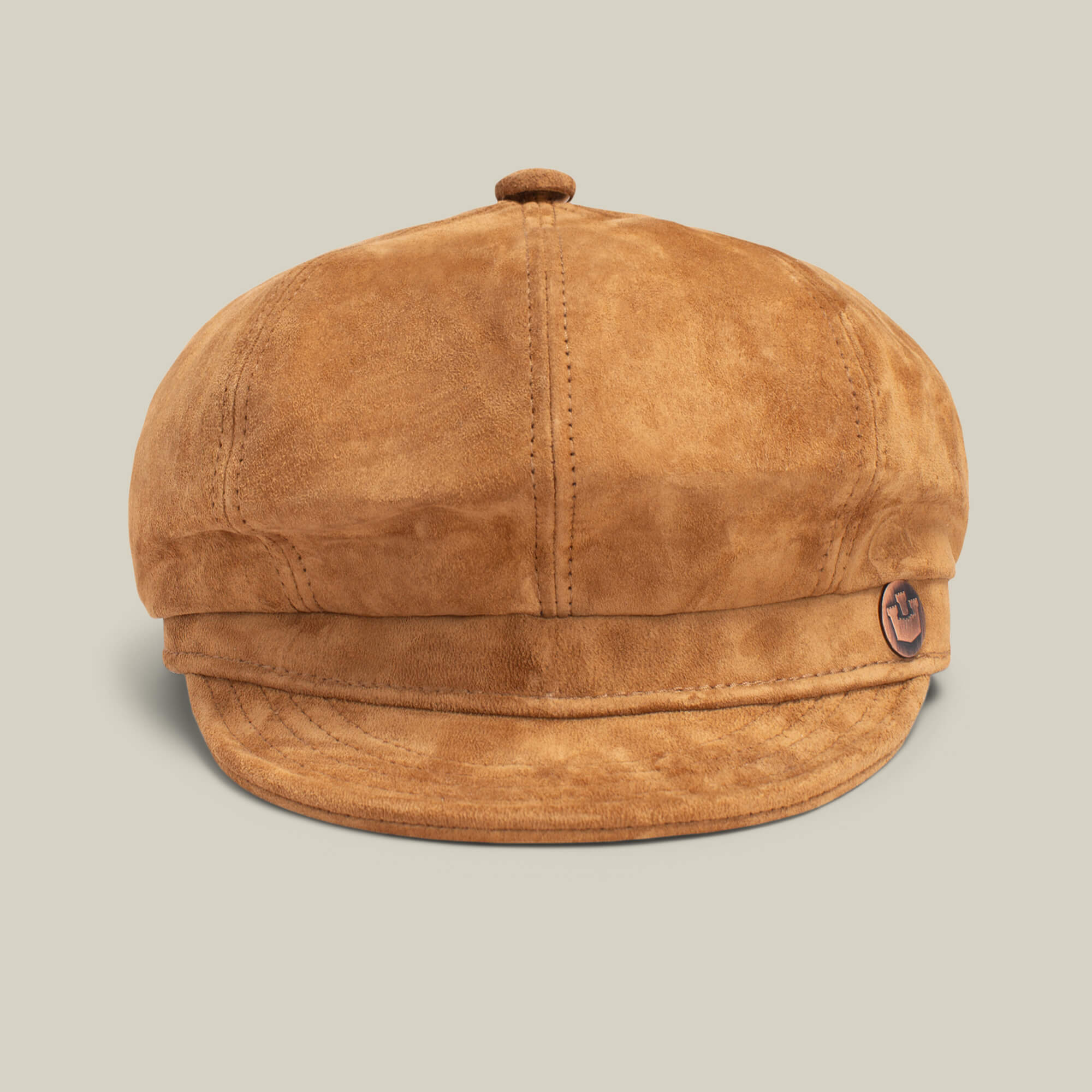The Ruthy by Goorin Bros. is a brown suede newsboy cap featuring visible stitching and a small anchor emblem on the left, styled in classic cabbie flatcap fashion against a plain light background.