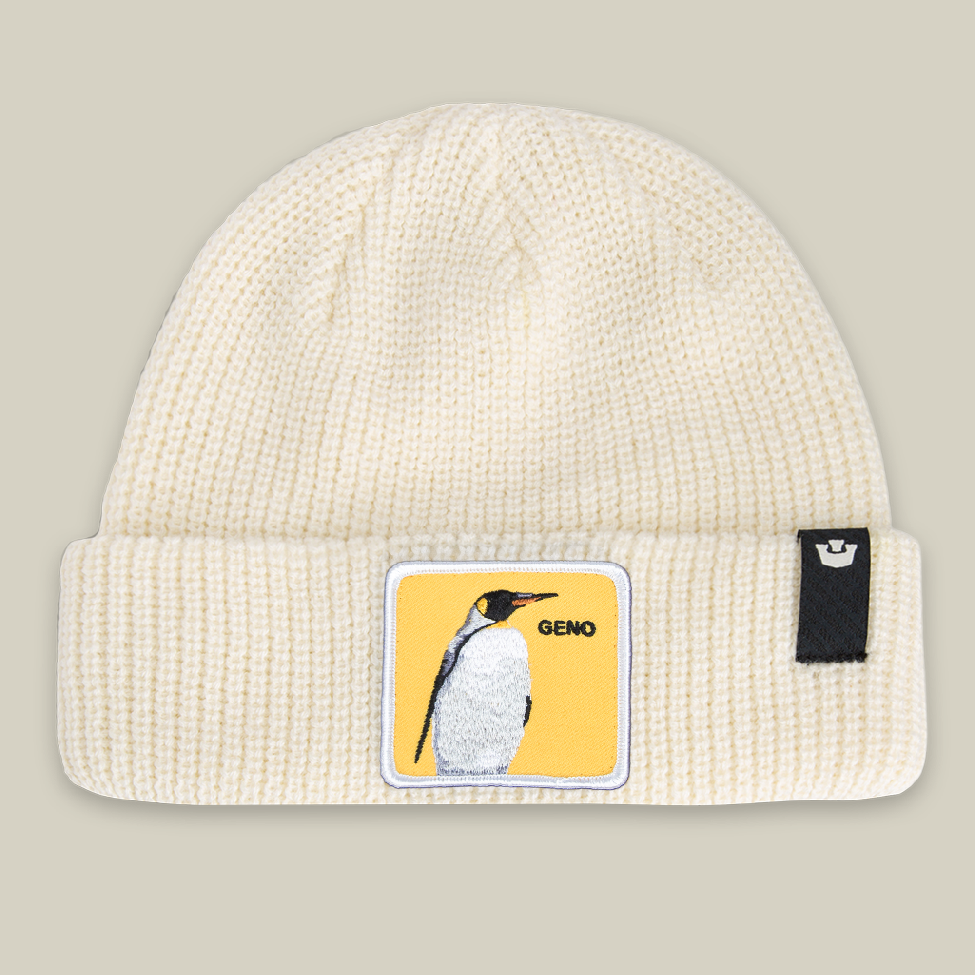 The Farm's "Warm Geno" is a cream knit beanie featuring a penguin patch with GENO on yellow, honoring Pittsburgh legend Evgeni Malkin, plus a small black tag on the cuff.