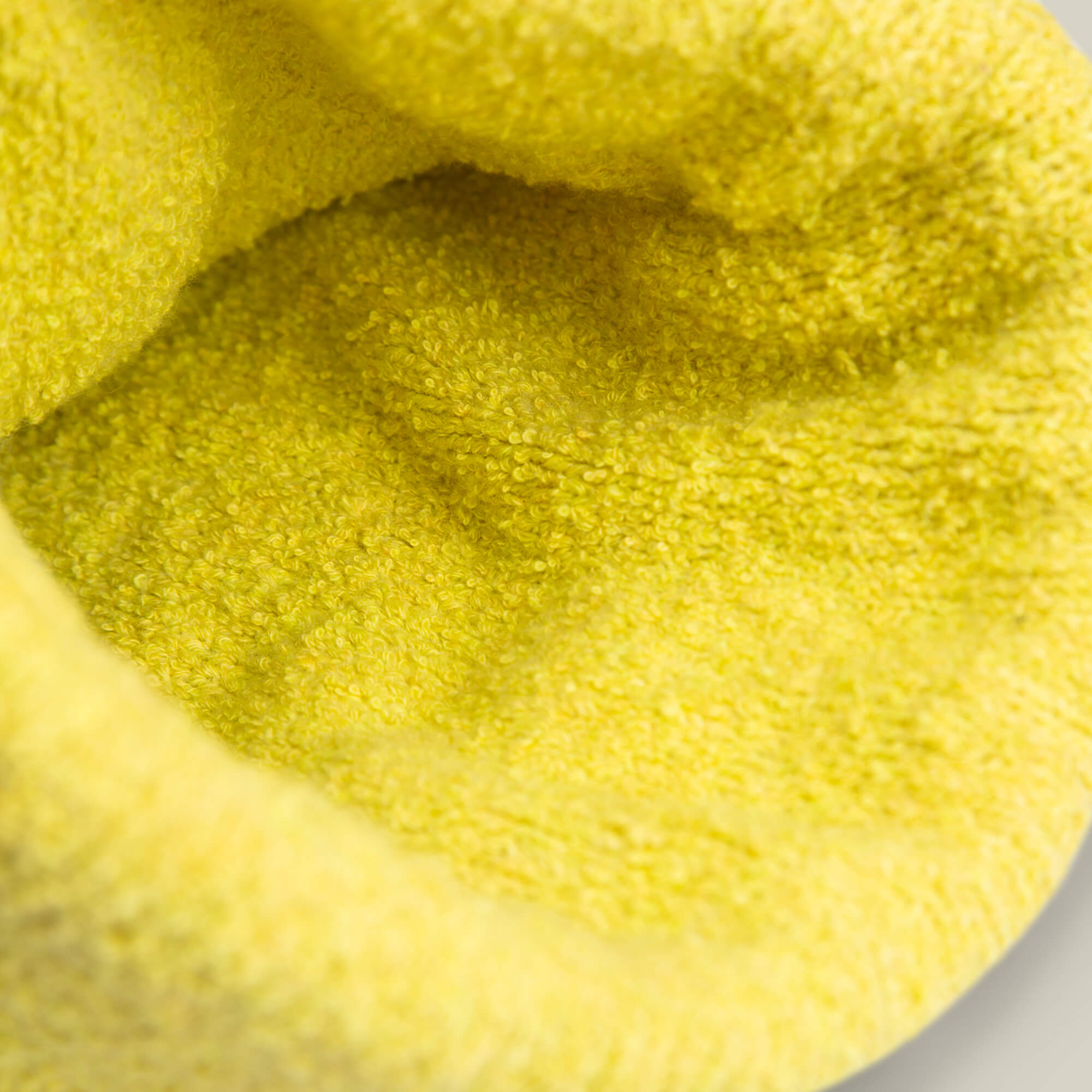 Close-up of soft, textured yellow fabric with looped fibers—evoking the cozy comfort of a sleepy bear beanie from Goorin Bros.' Nap World collection.