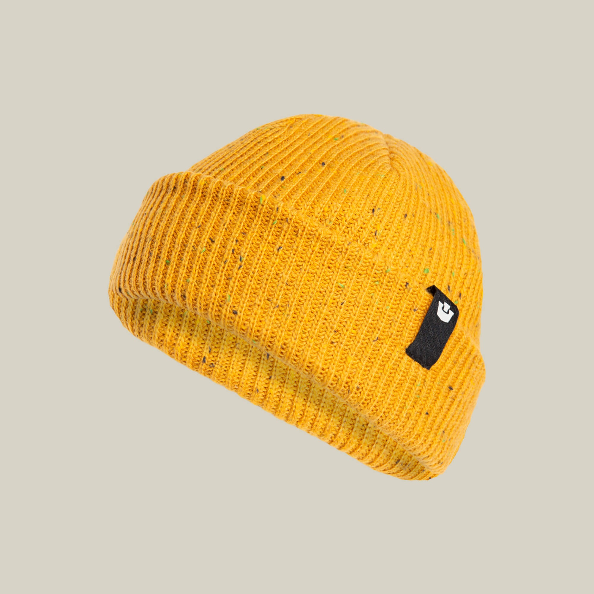The No Comply beanie by Goorin Bros. is a yellow ribbed knit hat featuring a folded brim and a black rectangular patch with a white logo on the side, displayed against a neutral background.