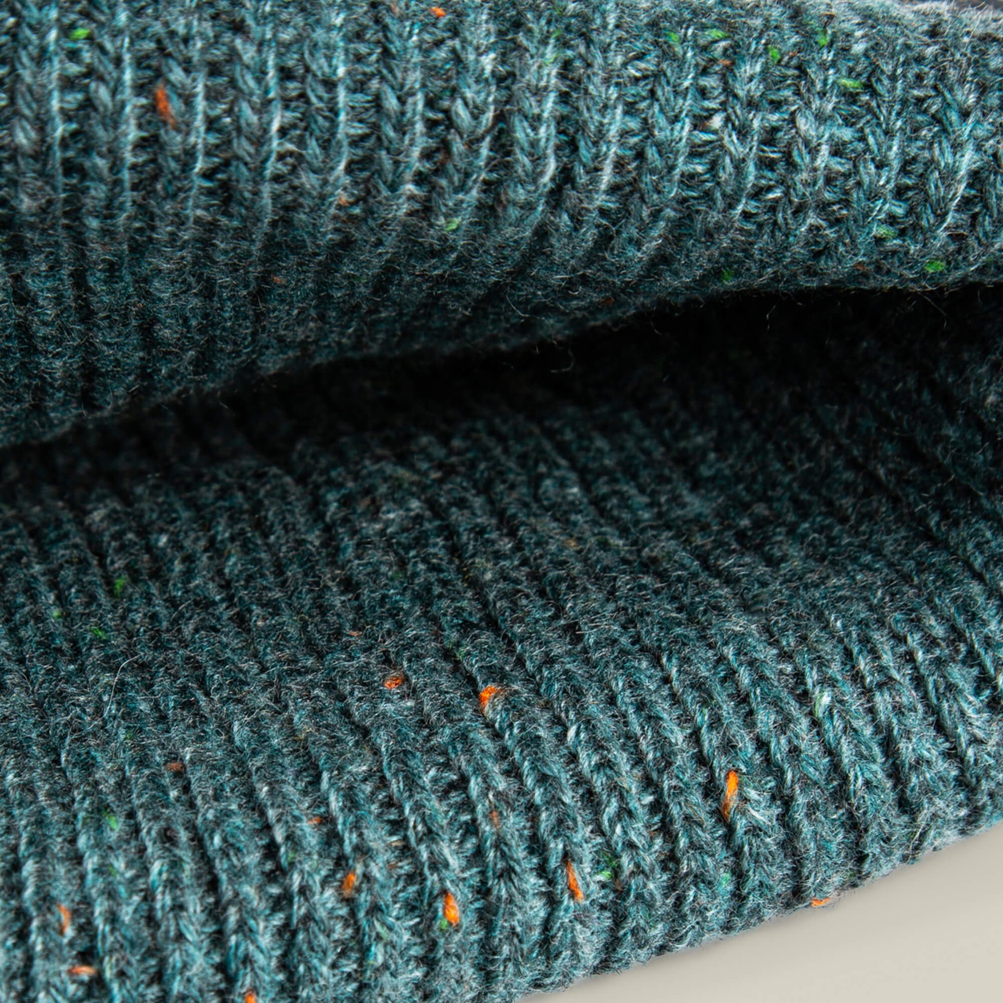 Close-up of the No Comply ribbed knit fabric by Goorin Bros., featuring teal yarn with flecks of orange and green—perfect for a warm, comfortable beanie.