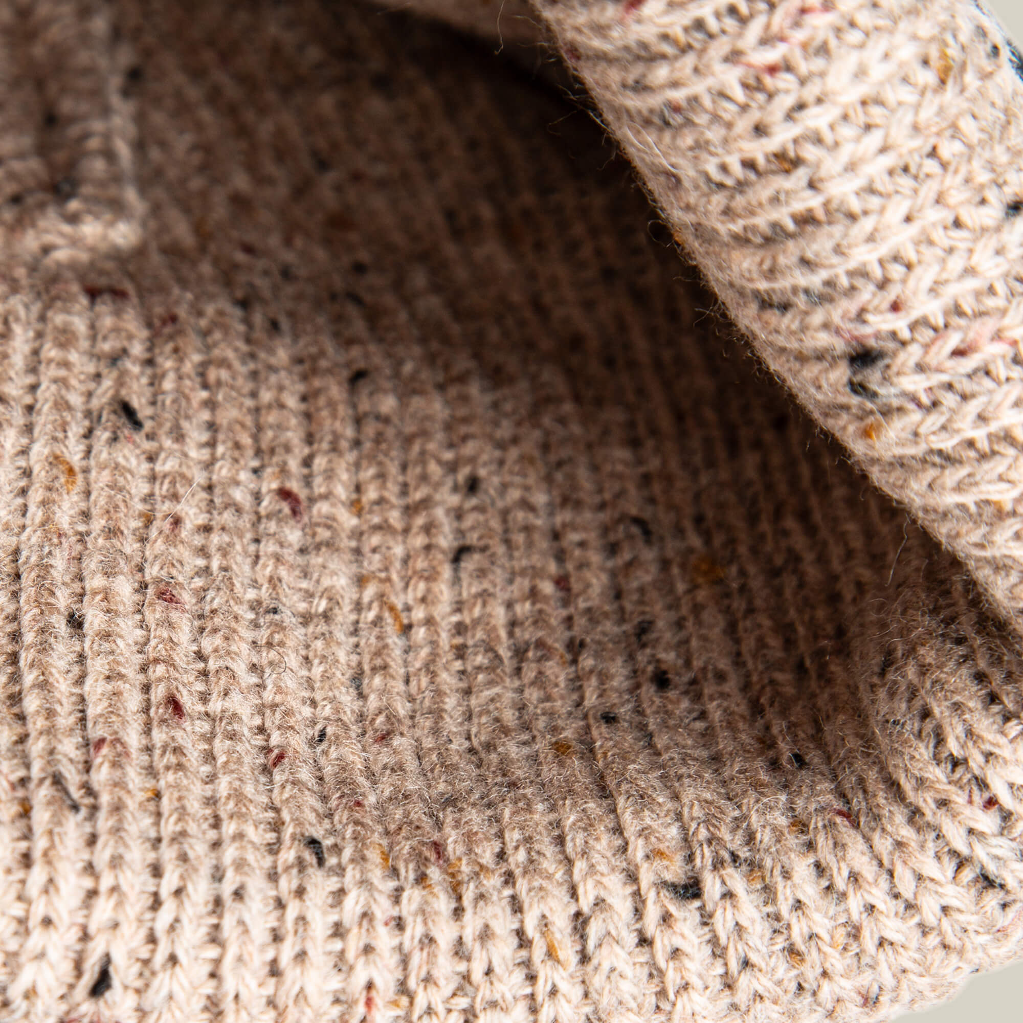 Close-up of the Goorin Bros. No Comply beanie's beige knit, highlighting its ribbed texture and small colored flecks woven throughout the fabric.