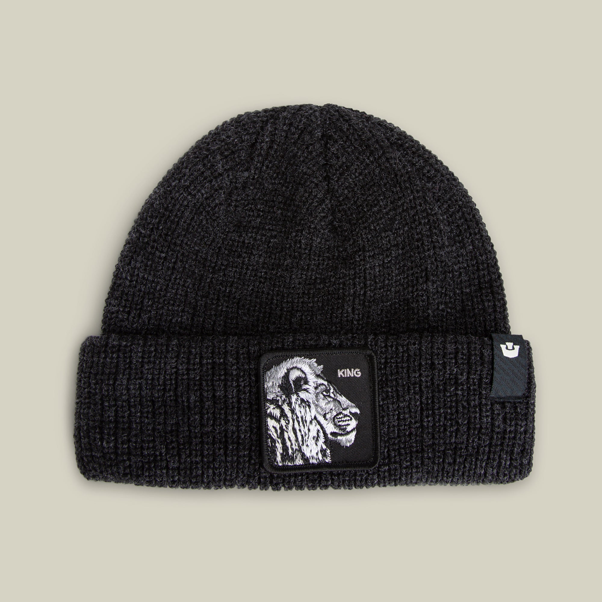 The Lion Beanie by Goorin Bros. in VOID features a heavyweight black cuff, a bold lion patch with "KING" on the front, and a small black tag with a white logo on the cuff.